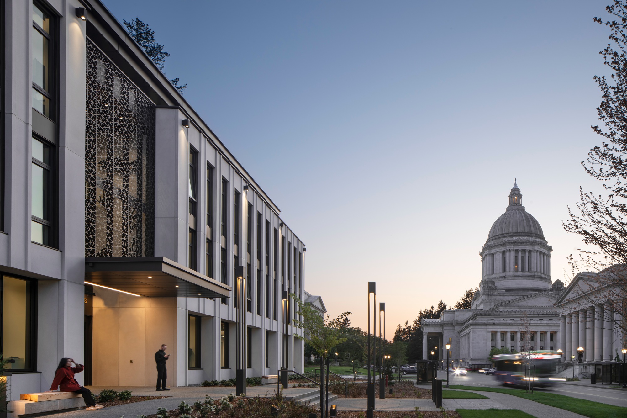 Evening view of the facade with illuminated entry and capitol dome visible under a gradient dusk sky