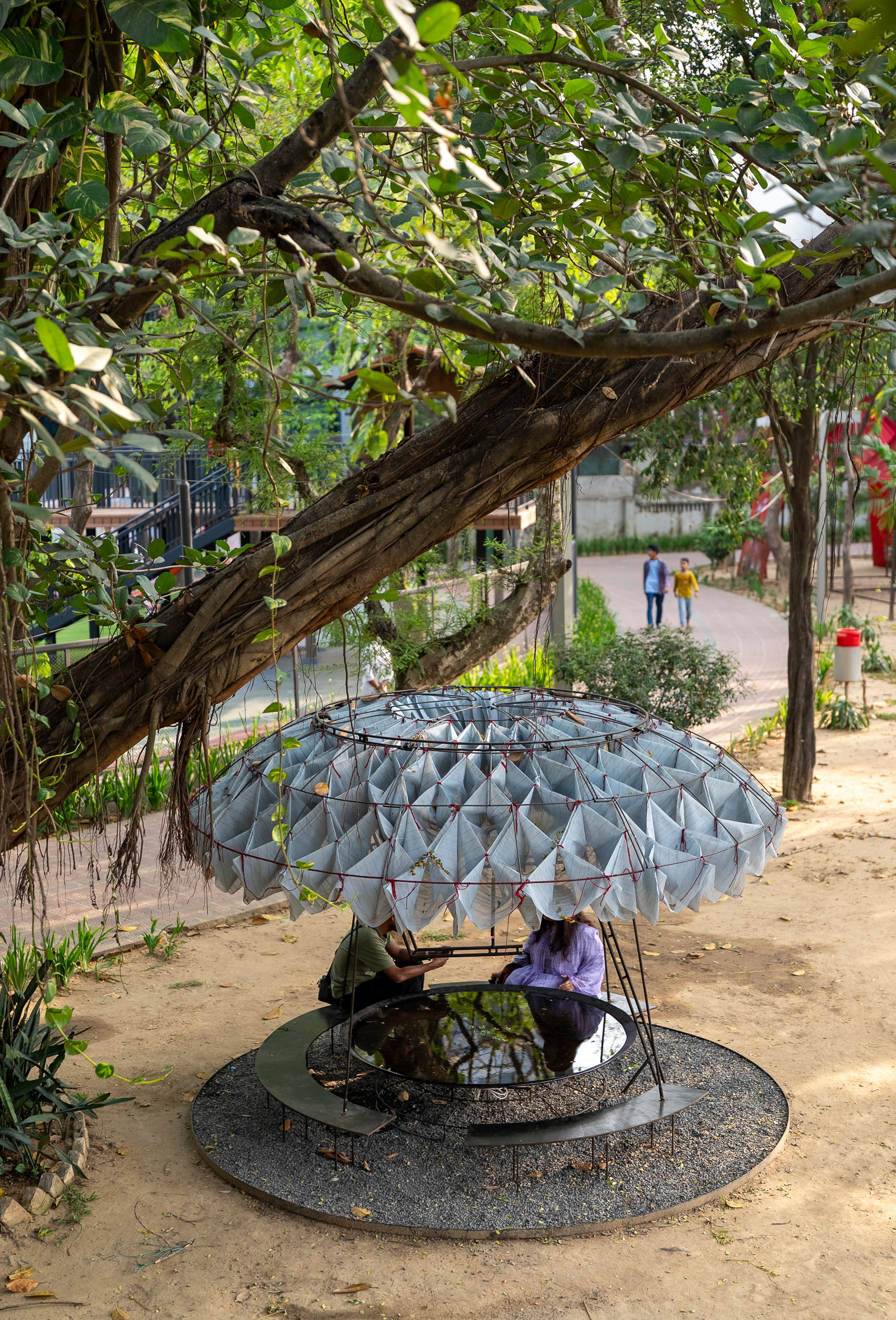Two people seated beneath the parasol canopy supported by thin steel rods and frame