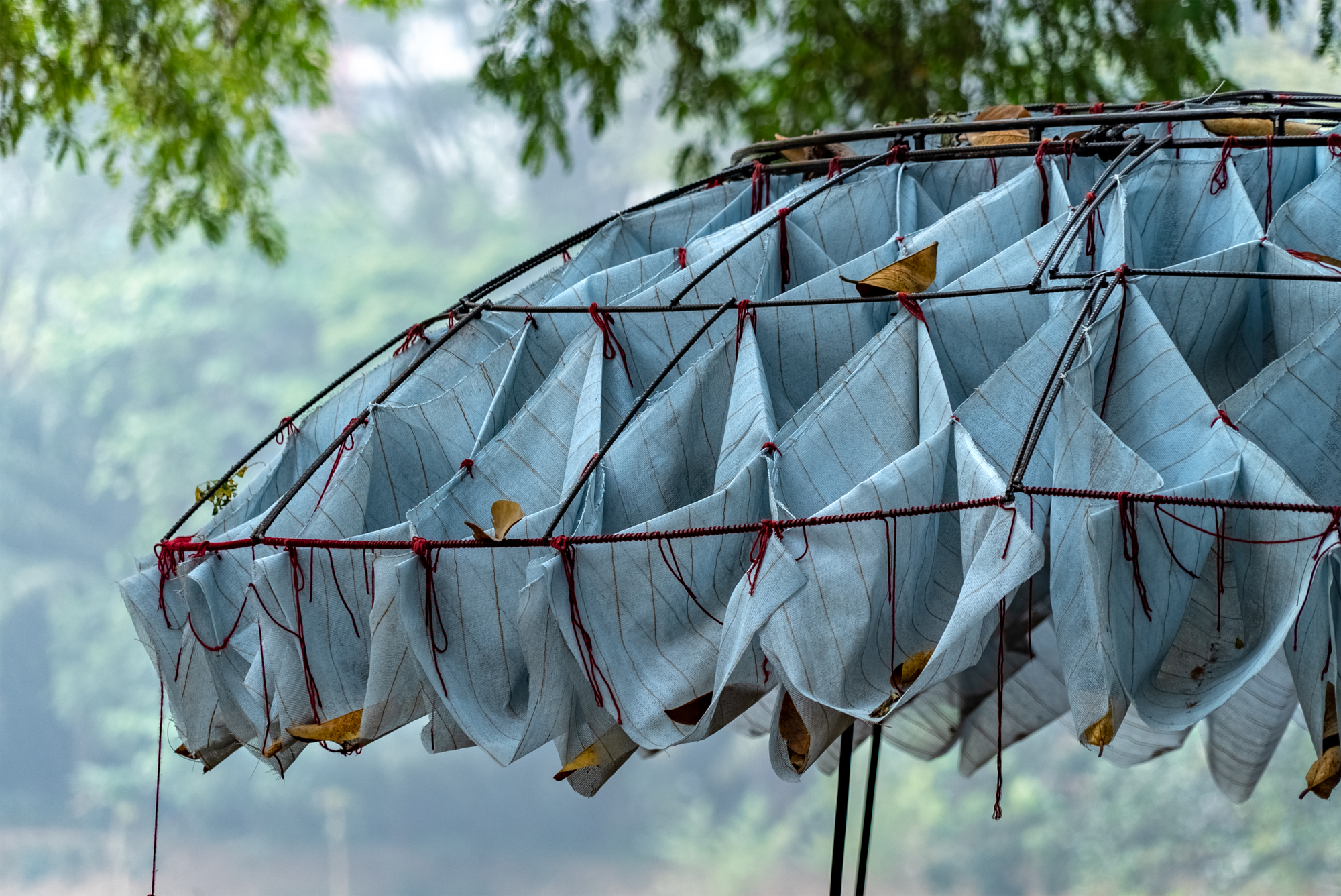 Close-up of the fabric scallops tied with cord to the metal frame with leaves caught