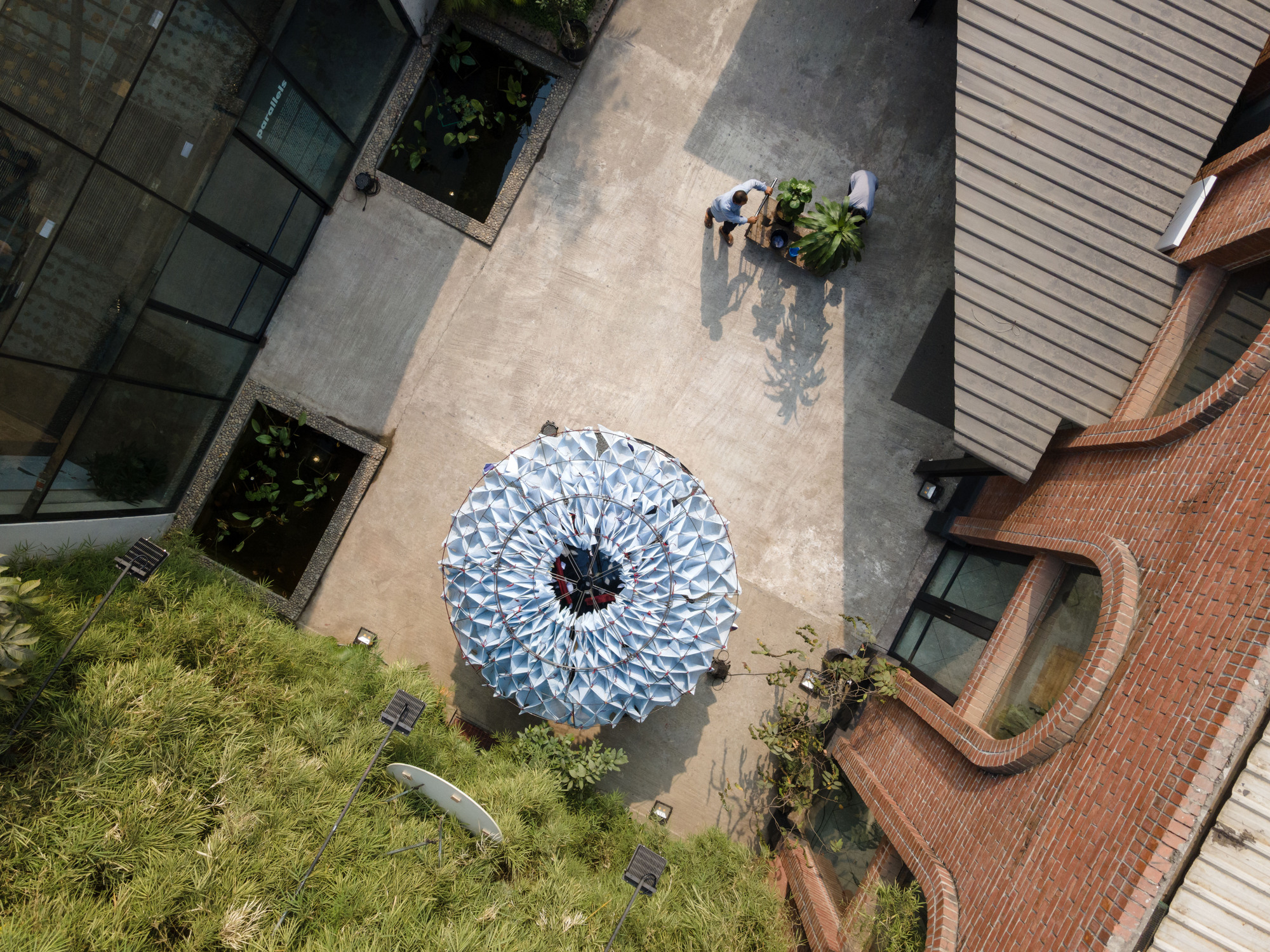 Overhead view of the circular pavilion in a courtyard between brick and glass buildings