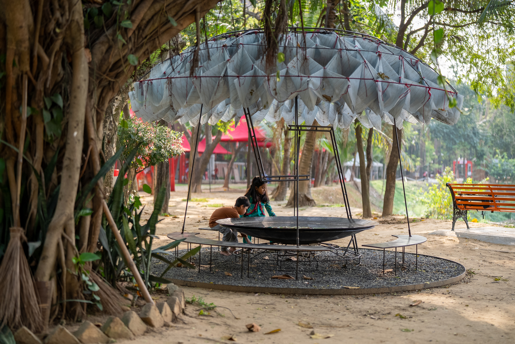 Pavilion structure nestled among tree roots and trunks in a park setting