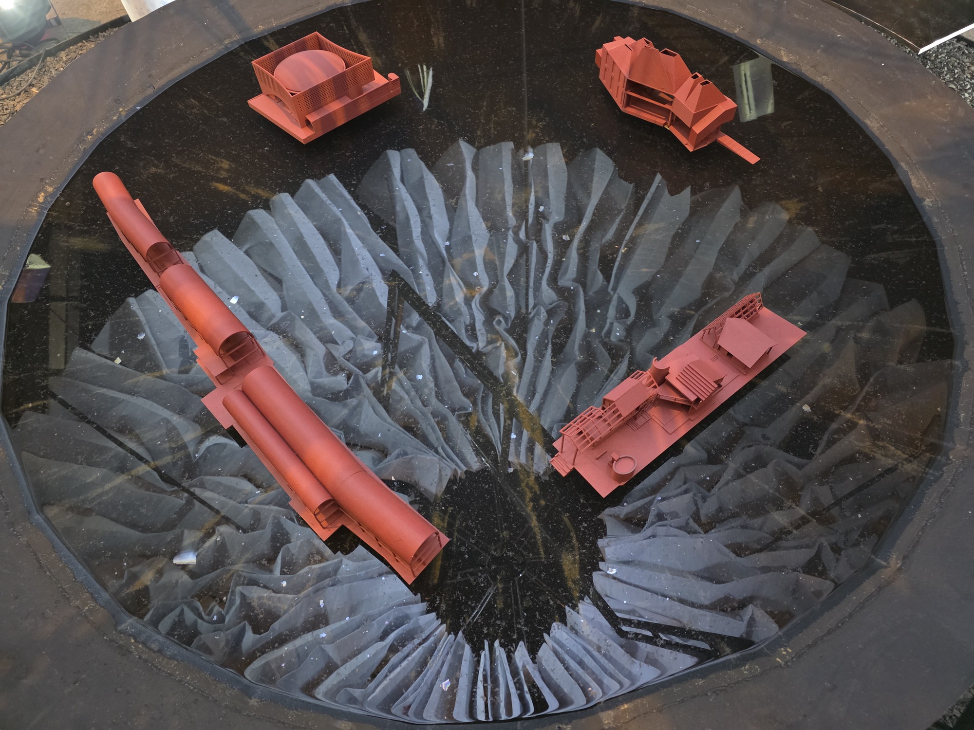 Overhead view of circular courtyard with radial paving and red sculptural models displayed at center