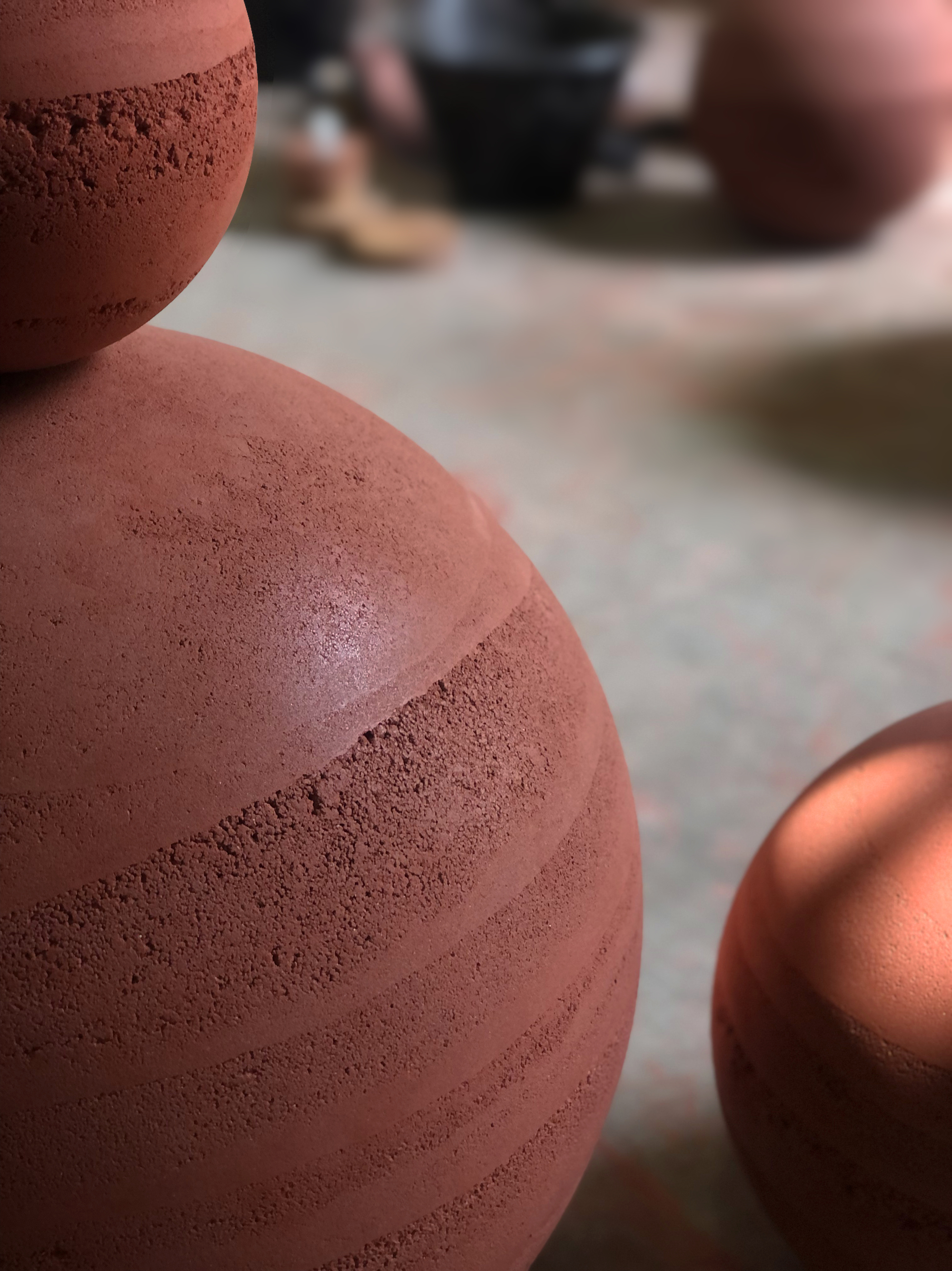 Close view of a terracotta sphere surface showing layered construction lines with a visitor passing behind