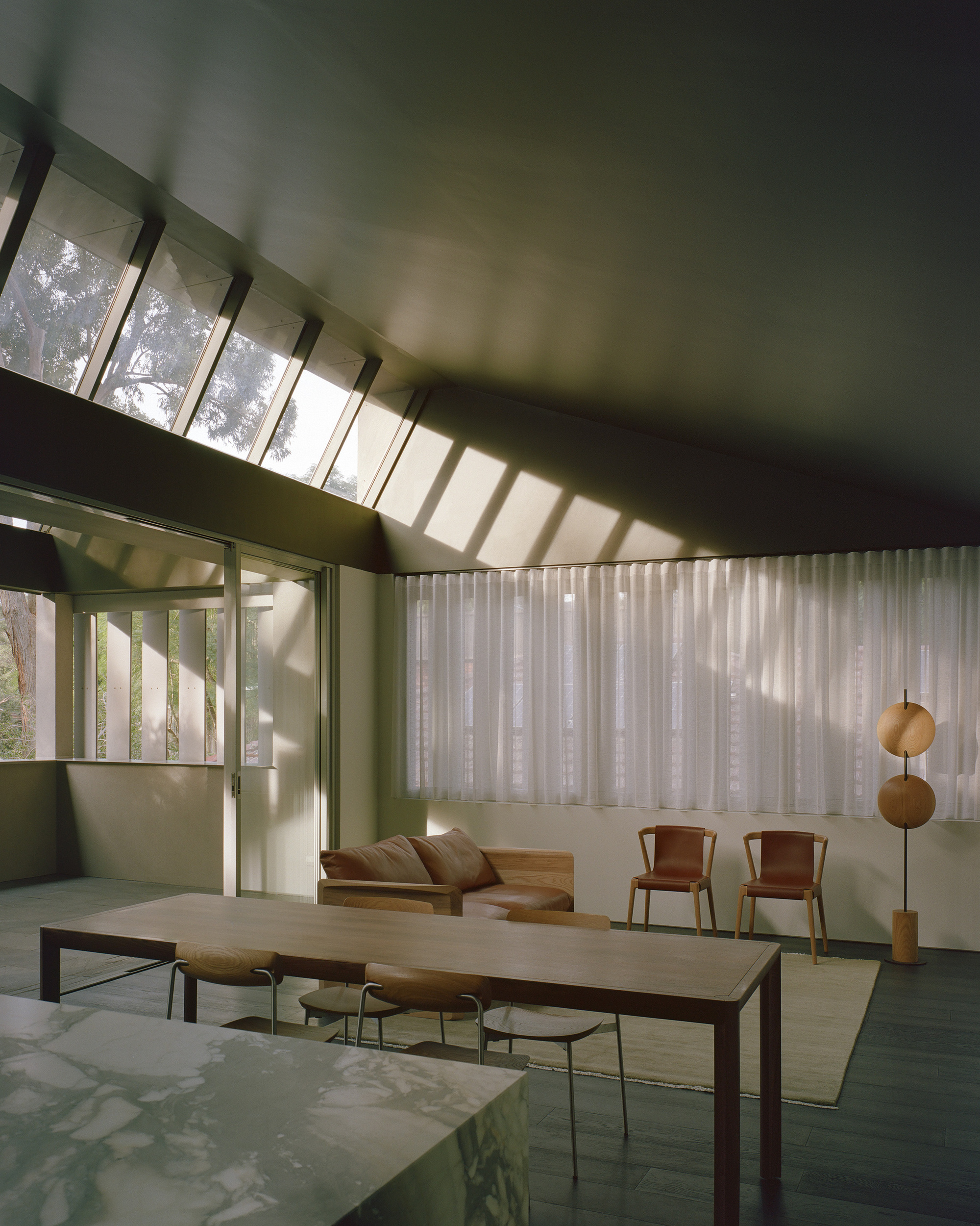 Angled clerestory windows above the dining space with light striping the green ceiling and walls