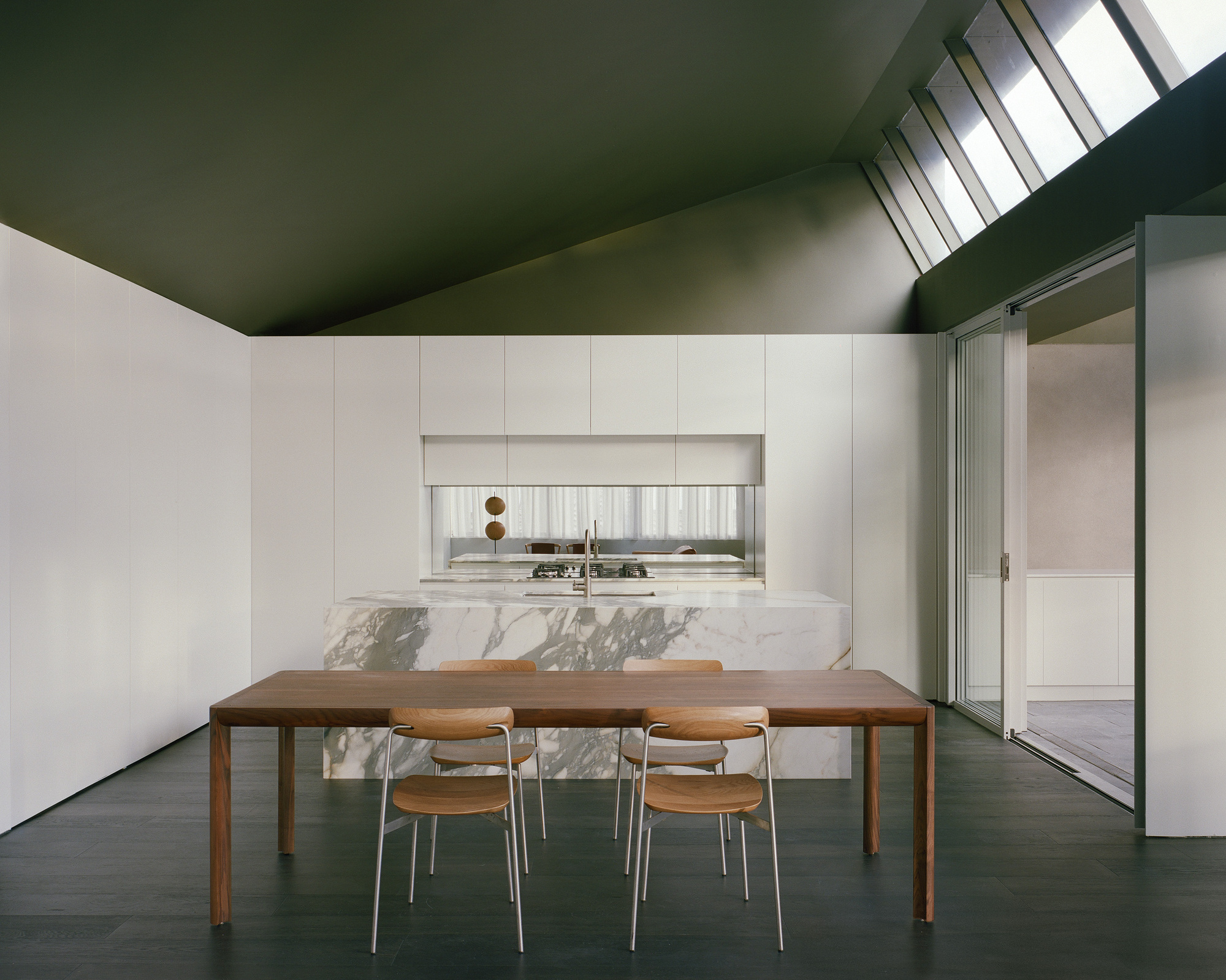 Kitchen with white cabinetry and marble waterfall island beneath a sloped green ceiling