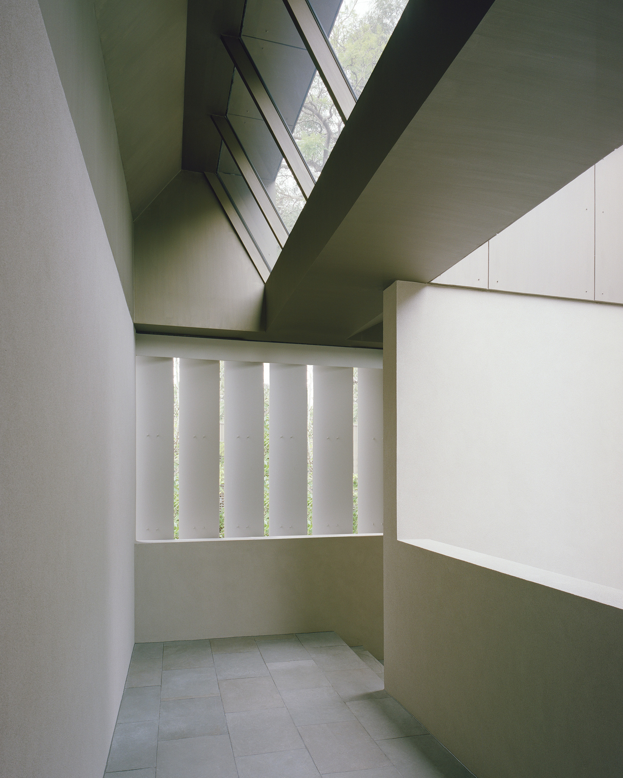 Interior corridor with vertical slot windows and clerestory glazing above white plaster walls