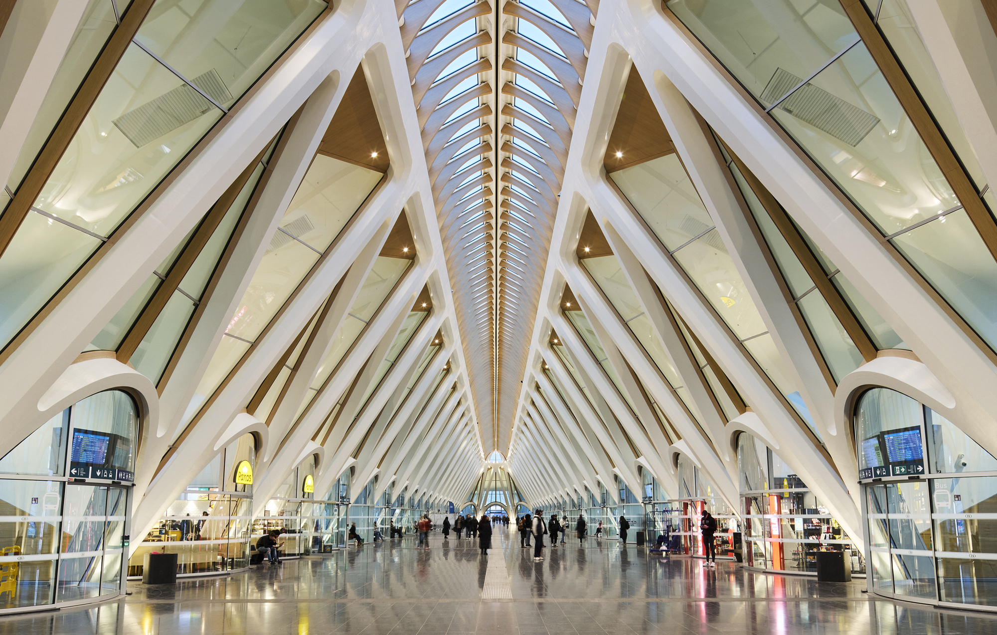 Interior concourse with radiating white arched ribs and central skylight above passengers