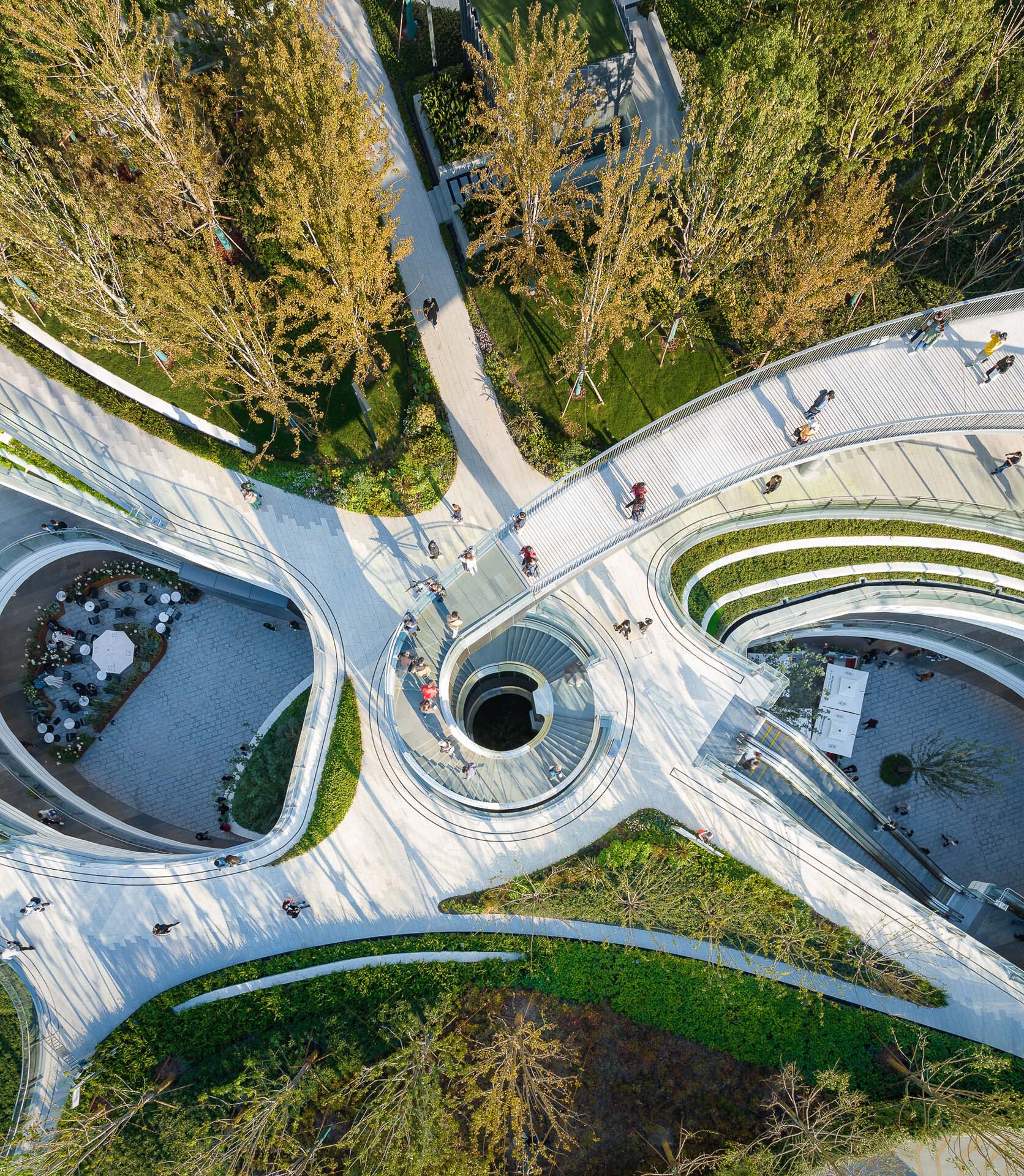Top-down view of concentric planted terraces radiating from a central circular skylight opening