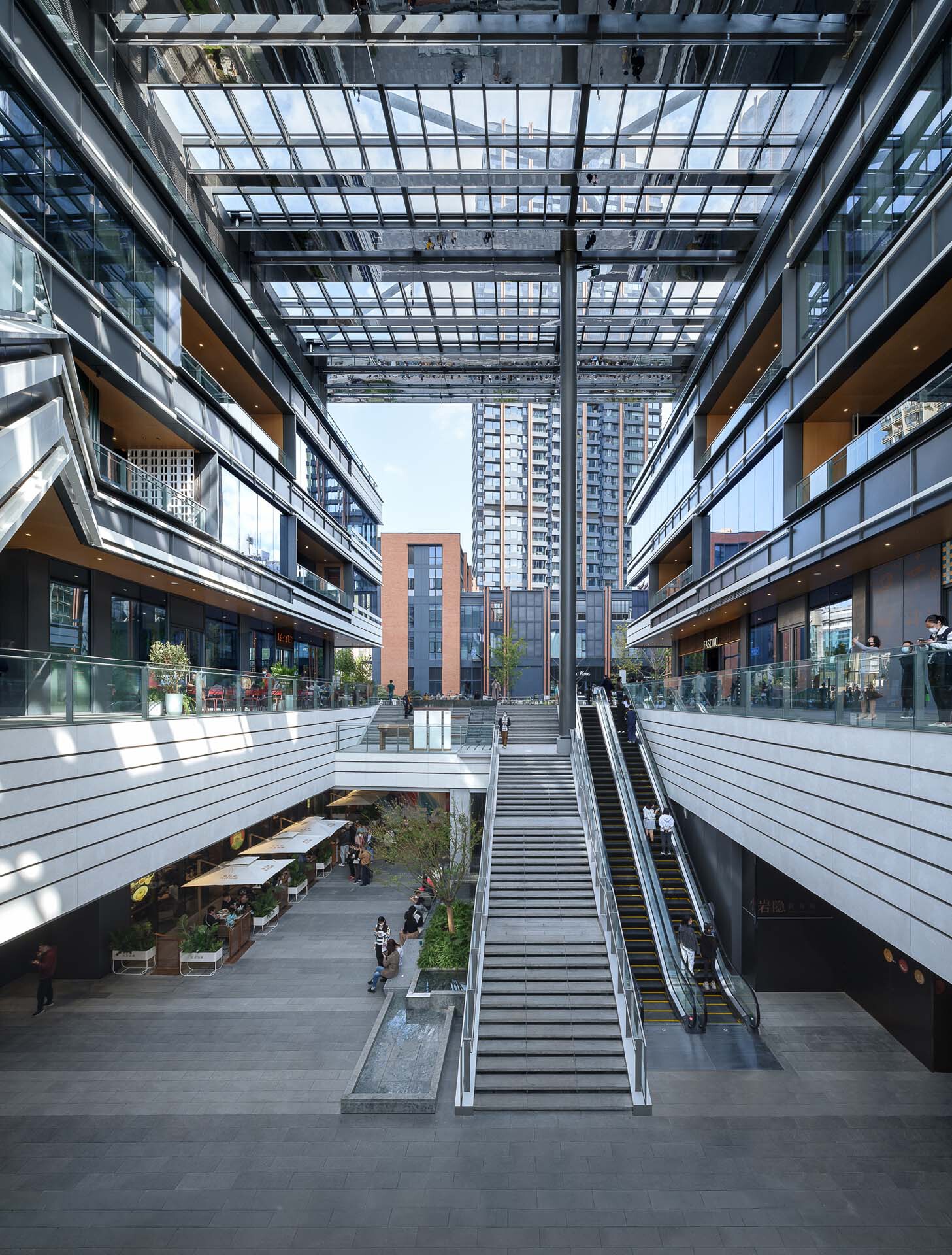 Central courtyard with escalators and stairs descending to a lower level beneath a glazed steel canopy