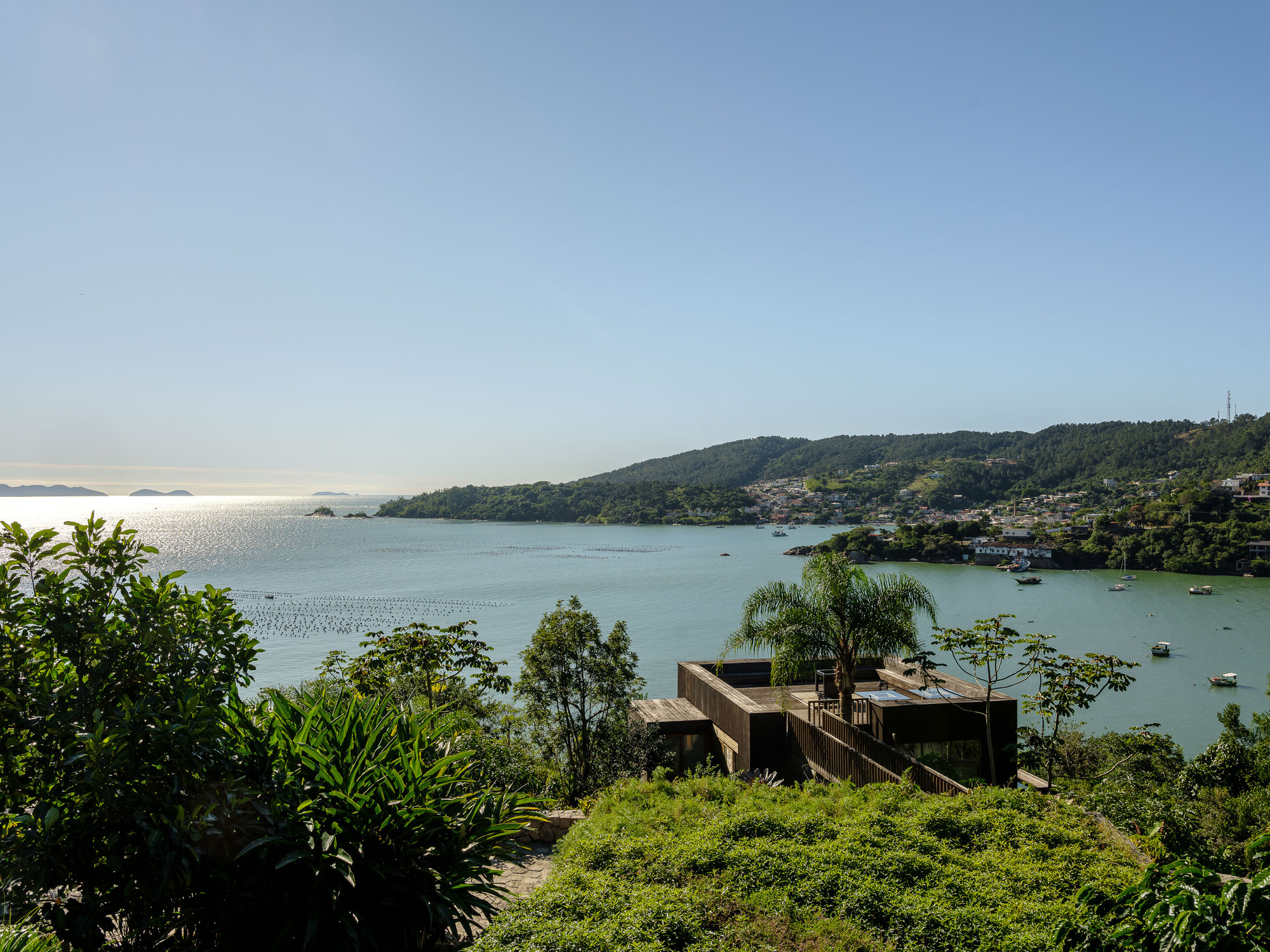 Long view of the low horizontal volume set into the sloping landscape overlooking the water