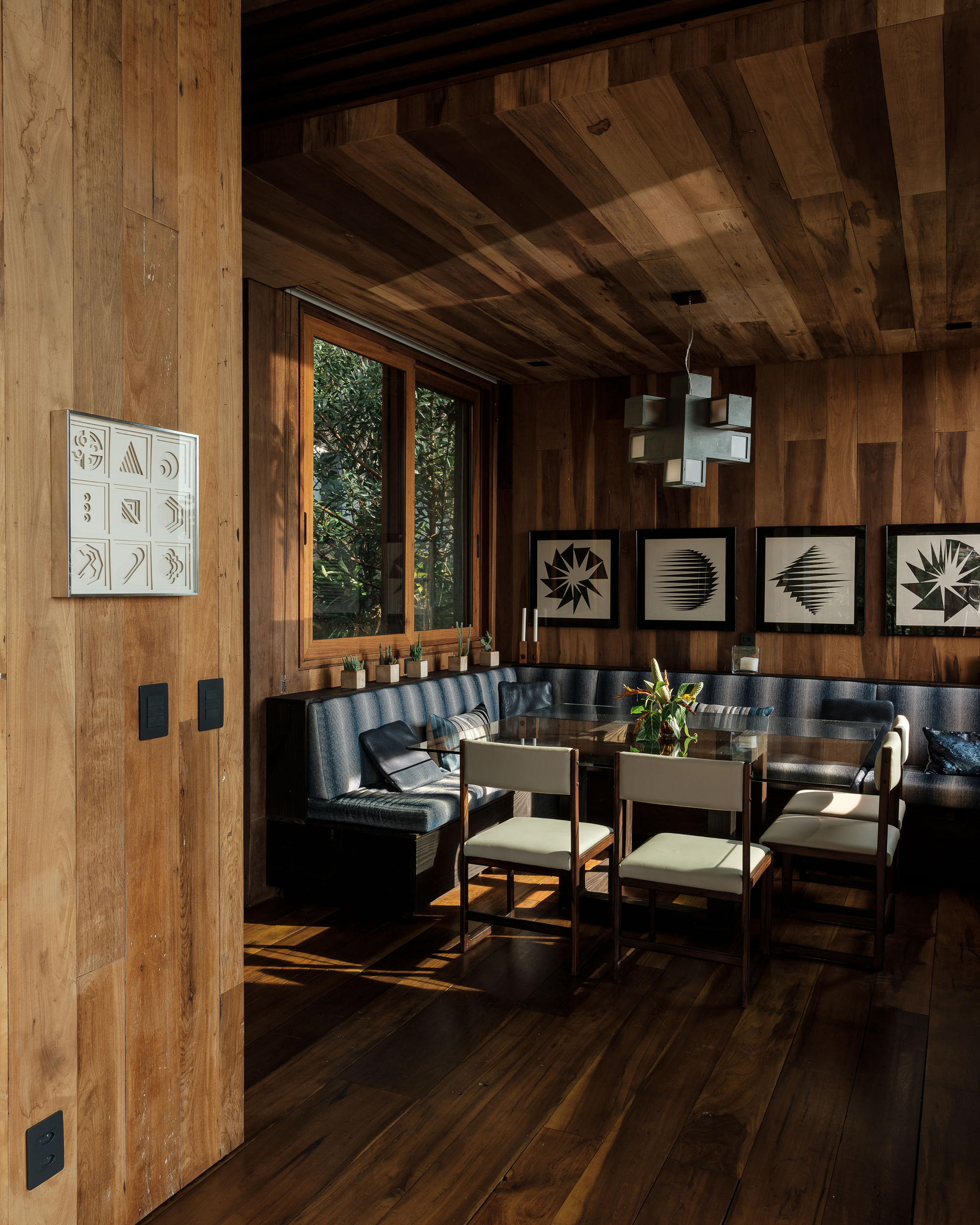 Wood-paneled dining area with exposed timber ceiling beams and built-in banquette seating beneath framed botanical prints