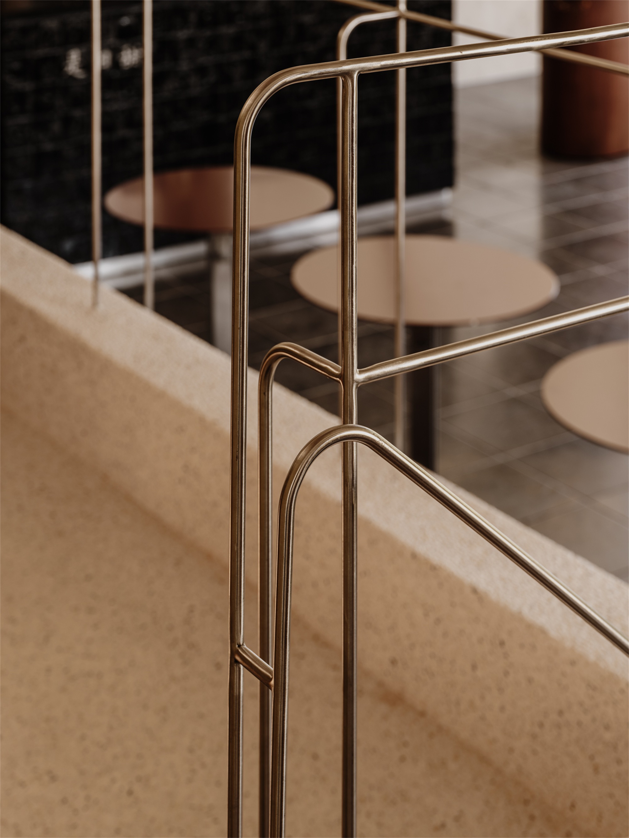 Detail of brass tubular railing anchored to terrazzo edge with curved corner joinery