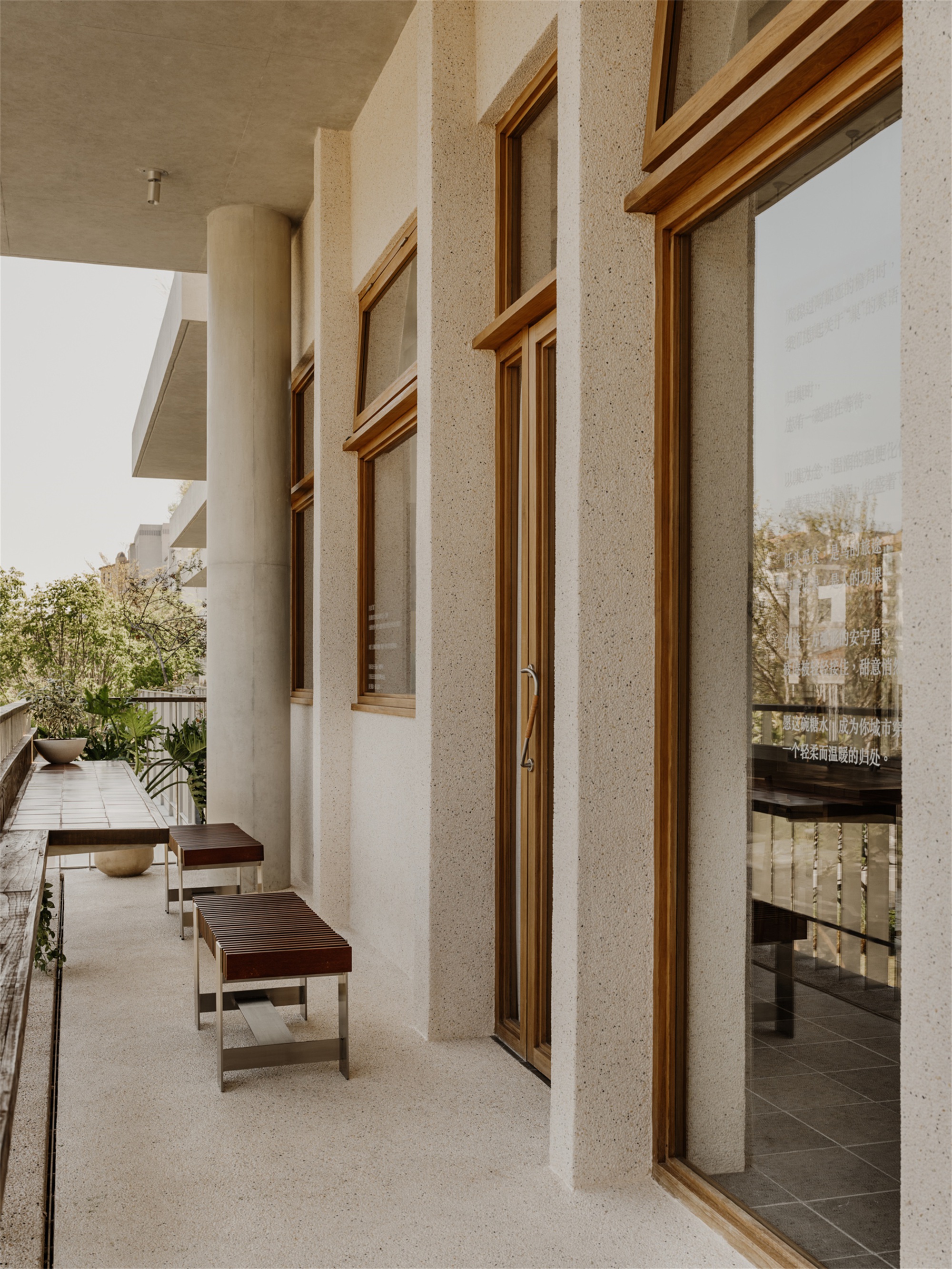 Exterior terrace with timber-framed windows set into terrazzo walls and cylindrical concrete column