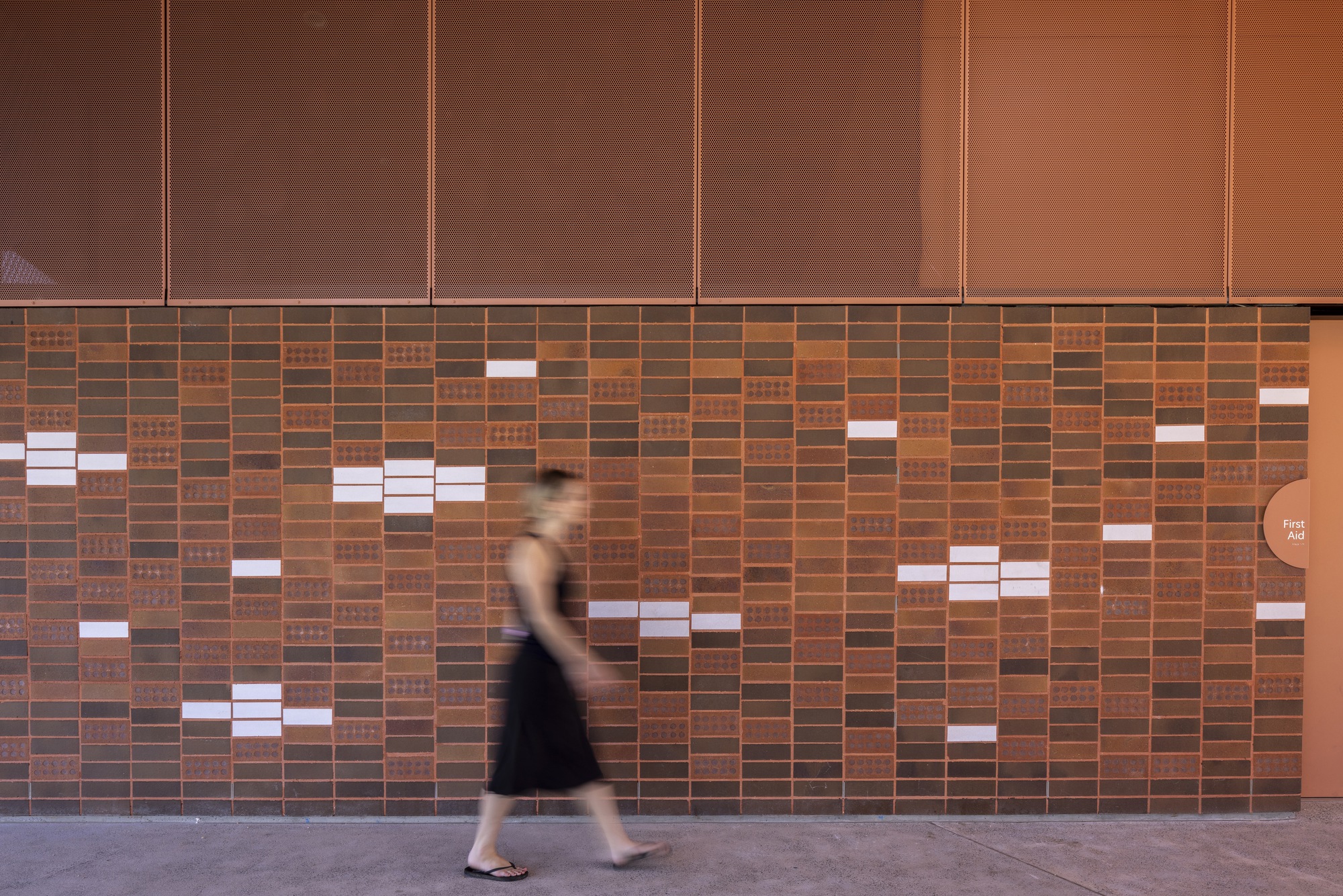 Patterned brick wall with scattered white ceramic tiles as a person walks past in motion blur