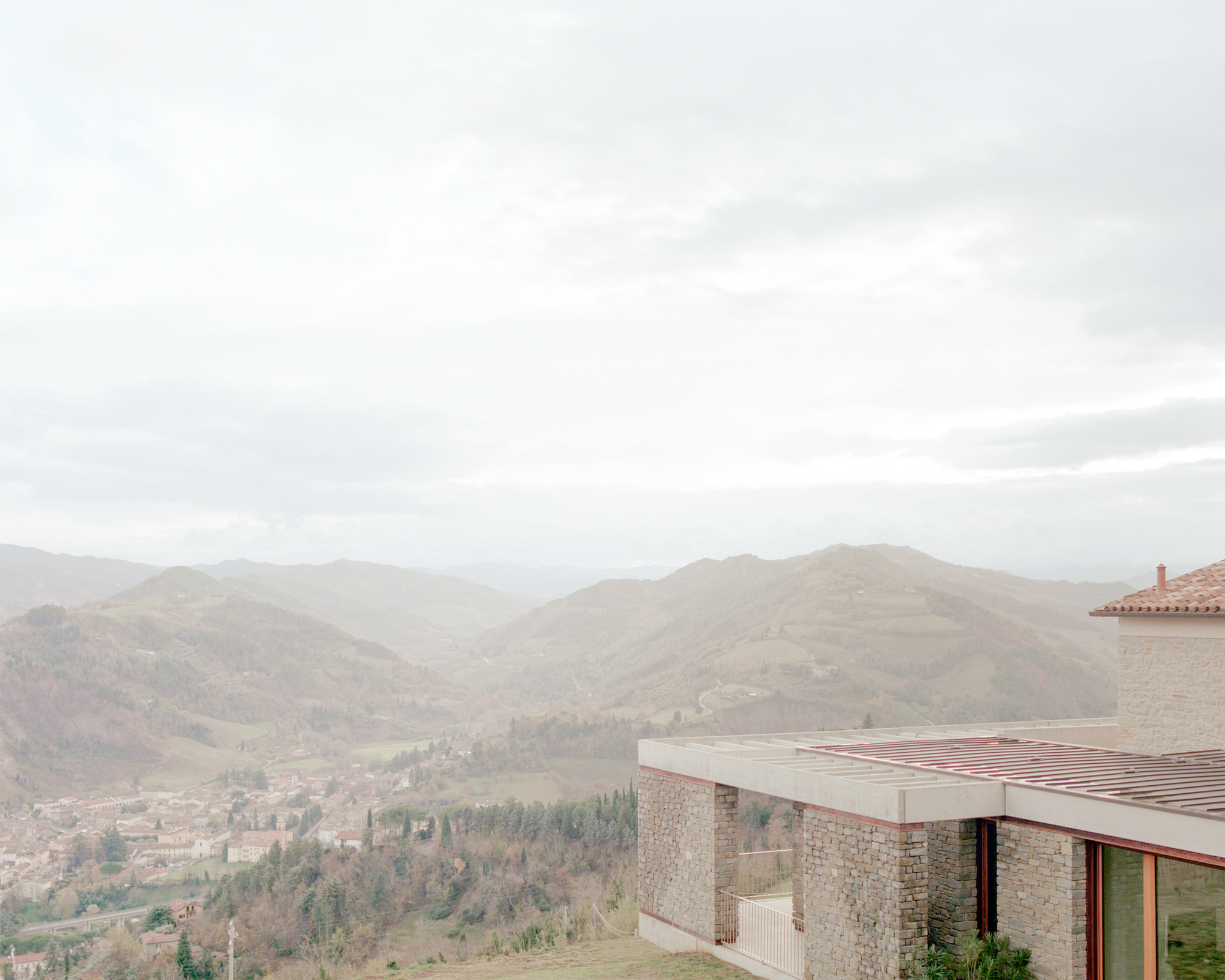 Flat roof terrace with timber battens overlooking a valley of distant hills in hazy light