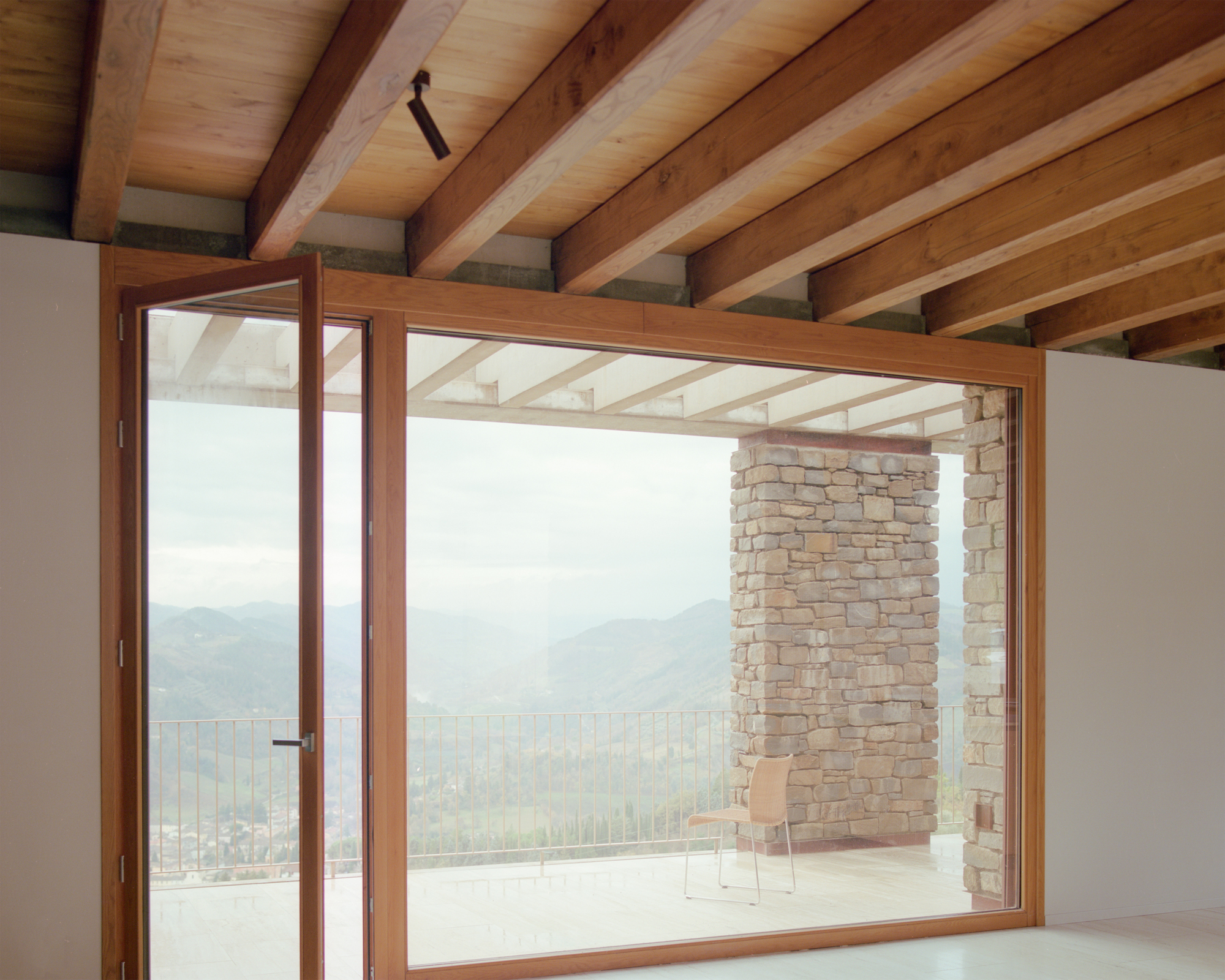 Timber-framed glazed doors opening to a terrace with mountain views and exposed beam ceiling above