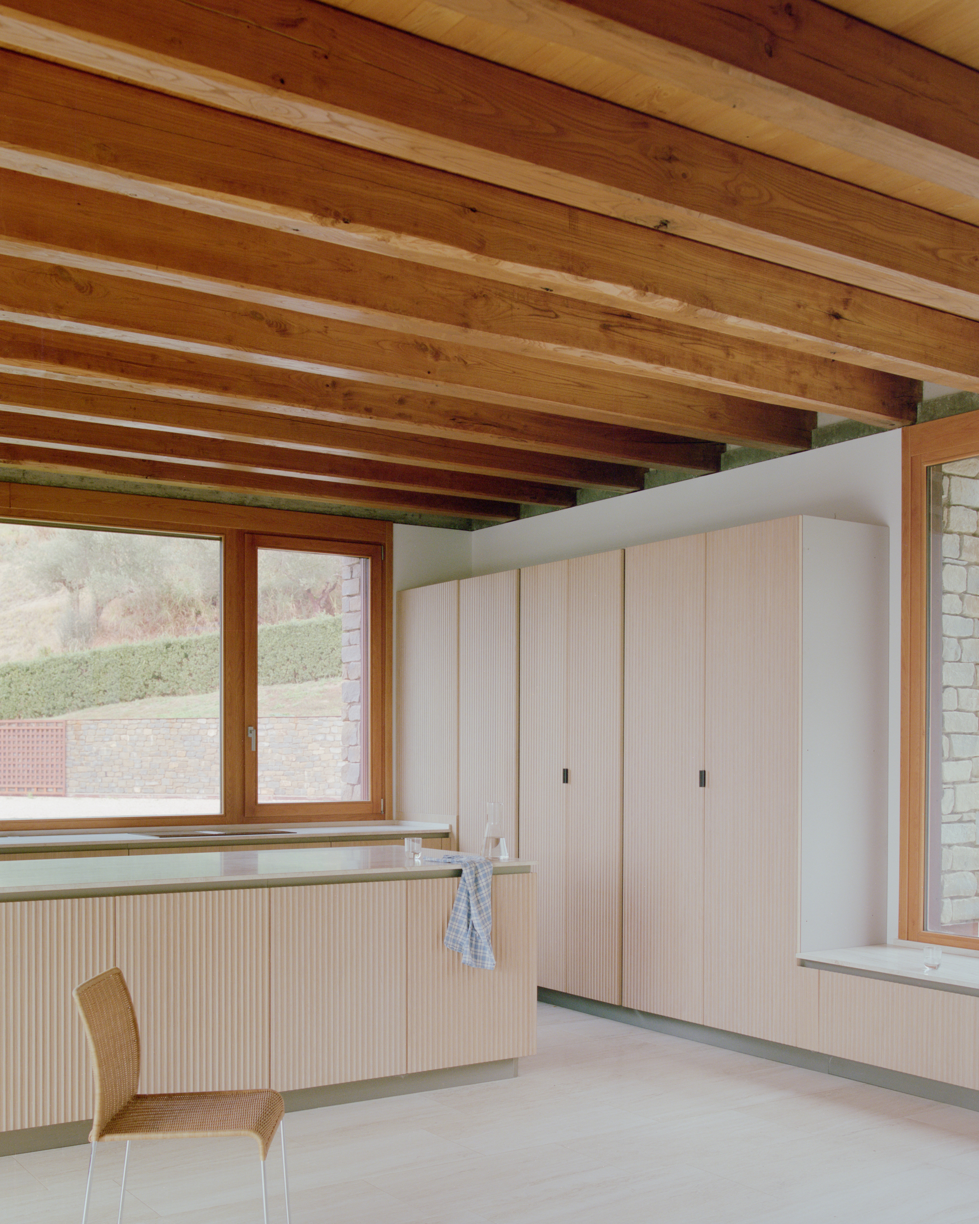 Interior room with exposed timber ceiling beams and pale wood built-in cabinetry along the walls