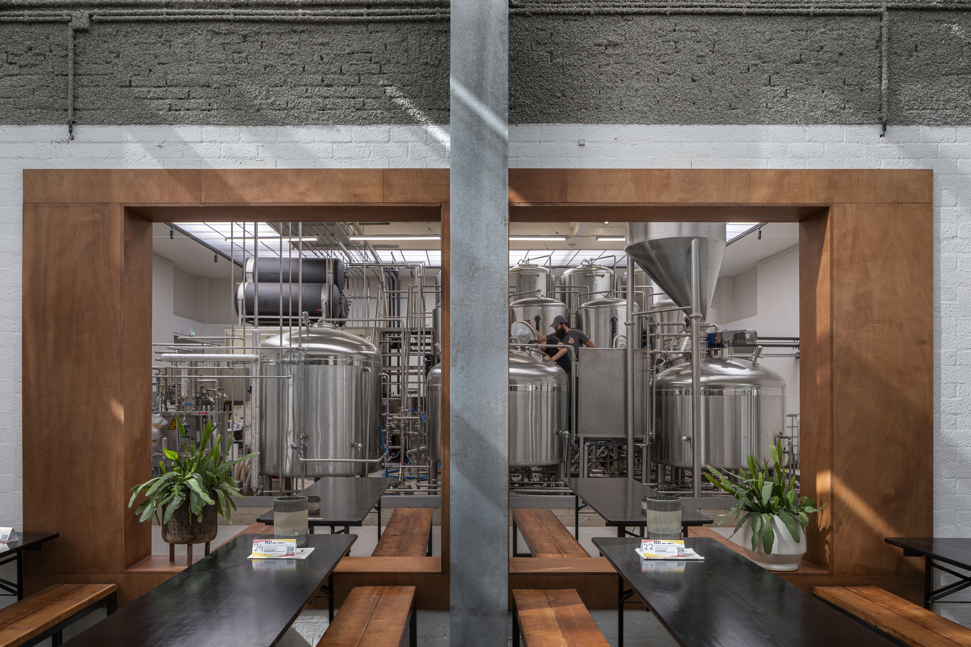 Timber-framed openings offering views into the brewery production floor from the seating area