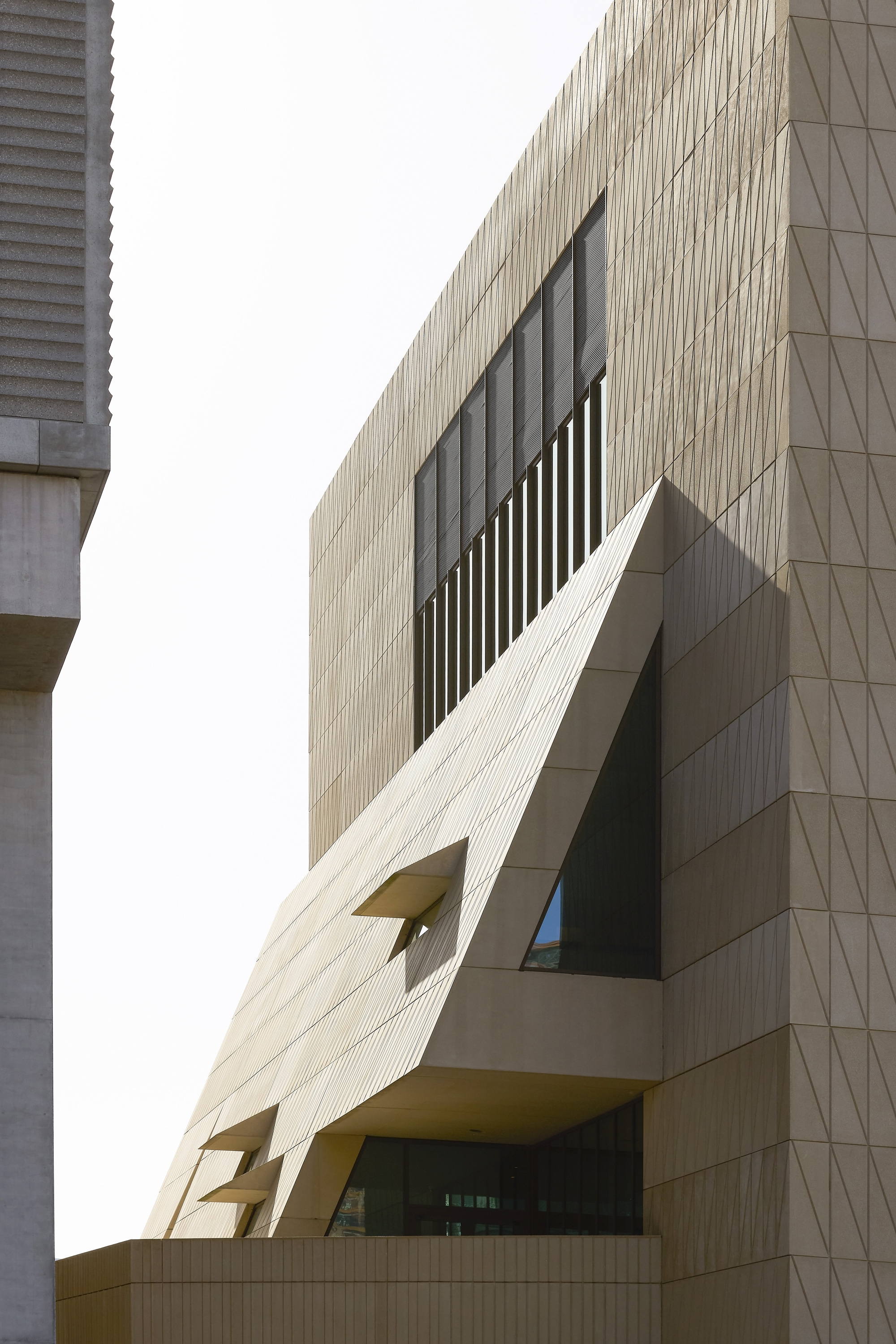 Close-up of the faceted cladding with vertical louvred window opening and projecting balcony