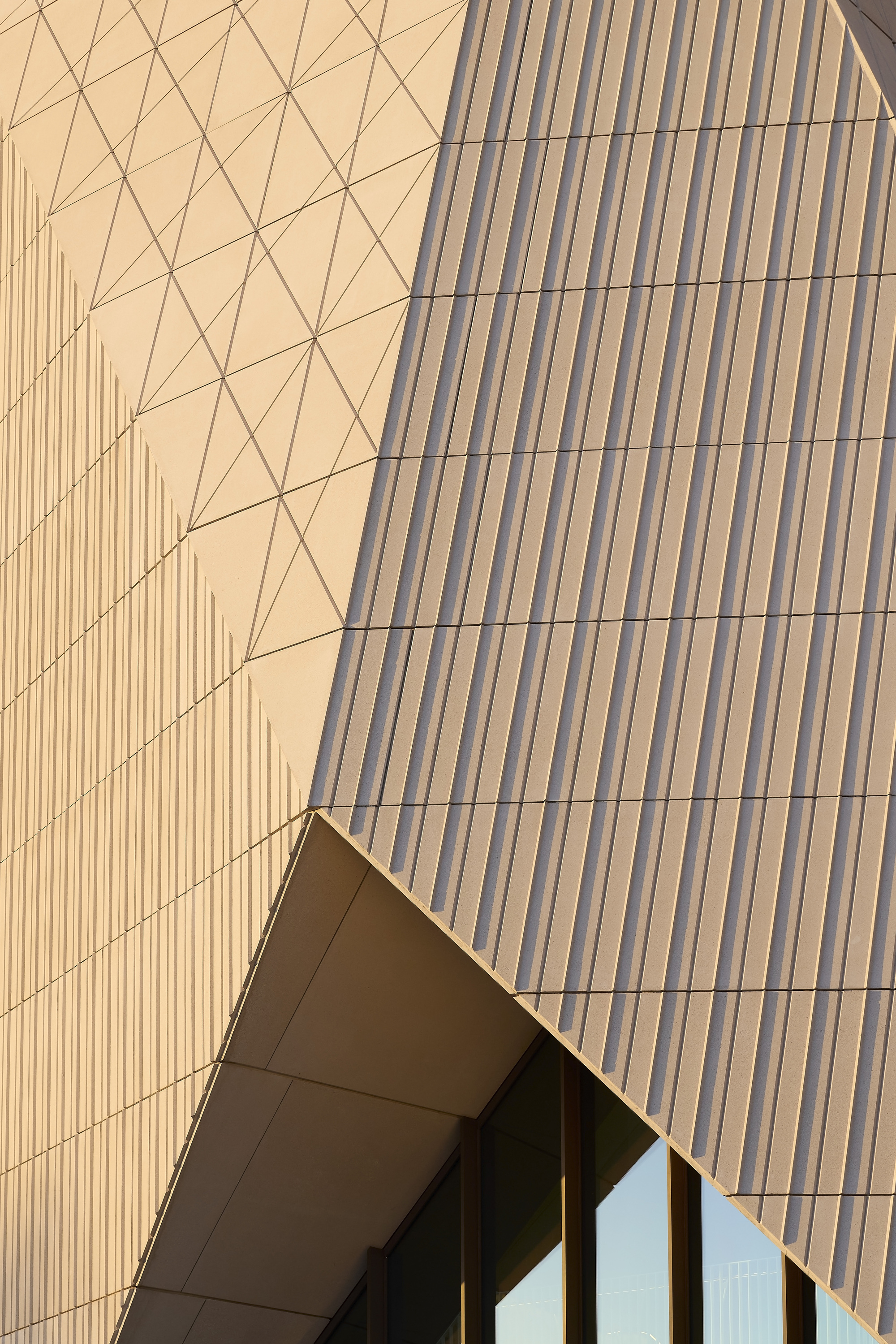 Facade detail showing triangular and vertical panel patterns meeting at an angular entrance canopy