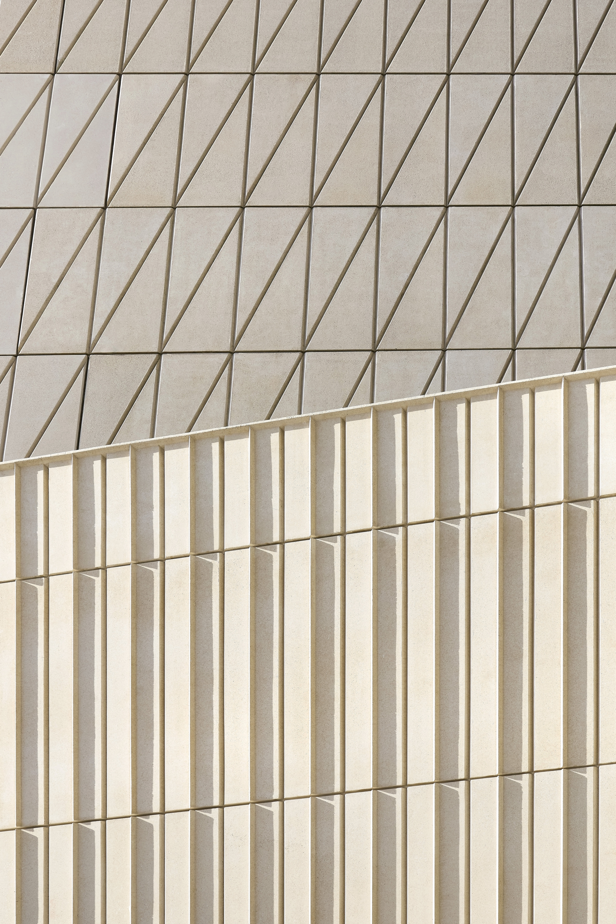 Two facade surfaces with contrasting patterns of diagonal grooves and vertical flutes meeting at a corner