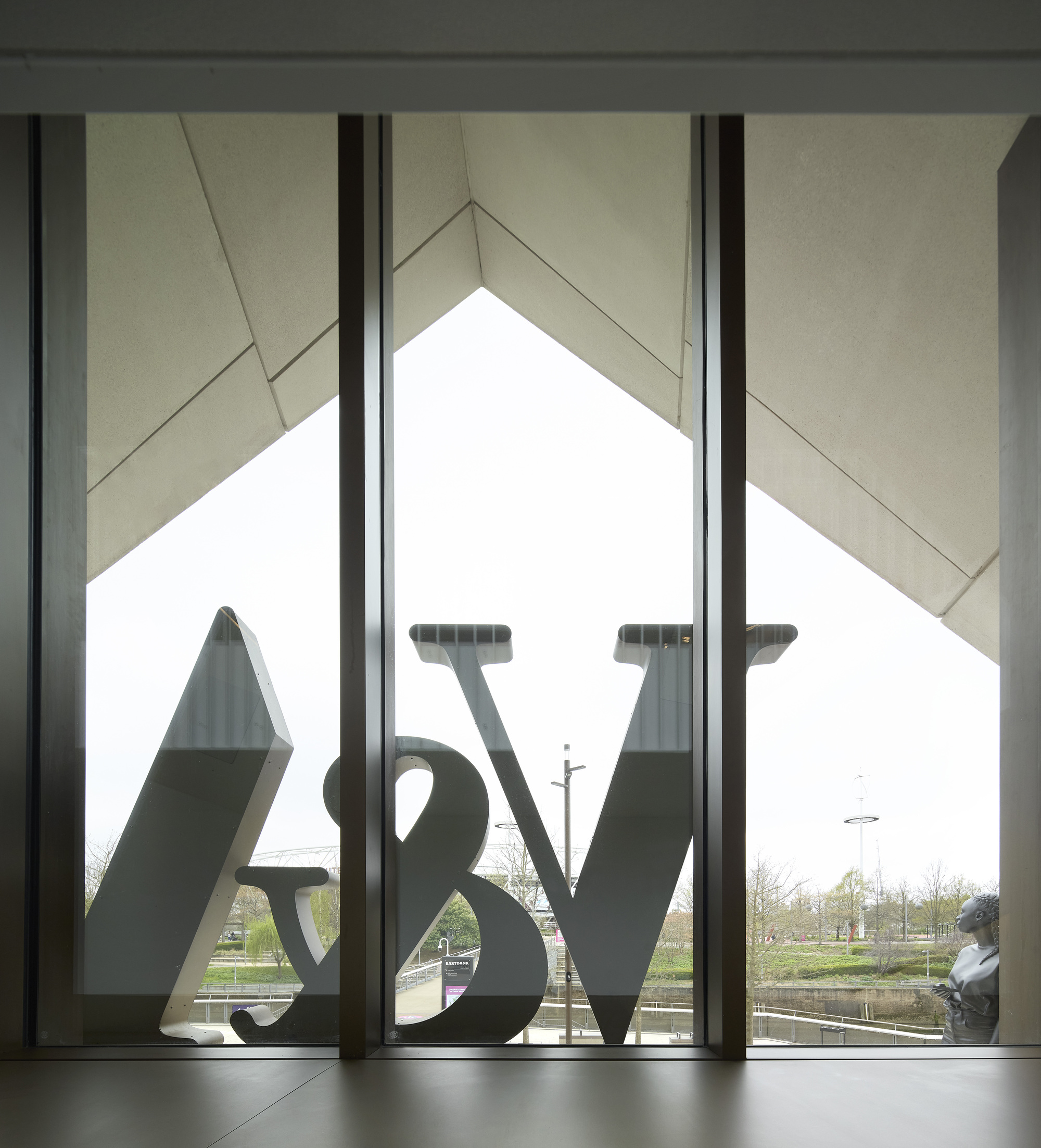 Interior view through the triangular window showing the sculpture logo silhouetted against pale sky