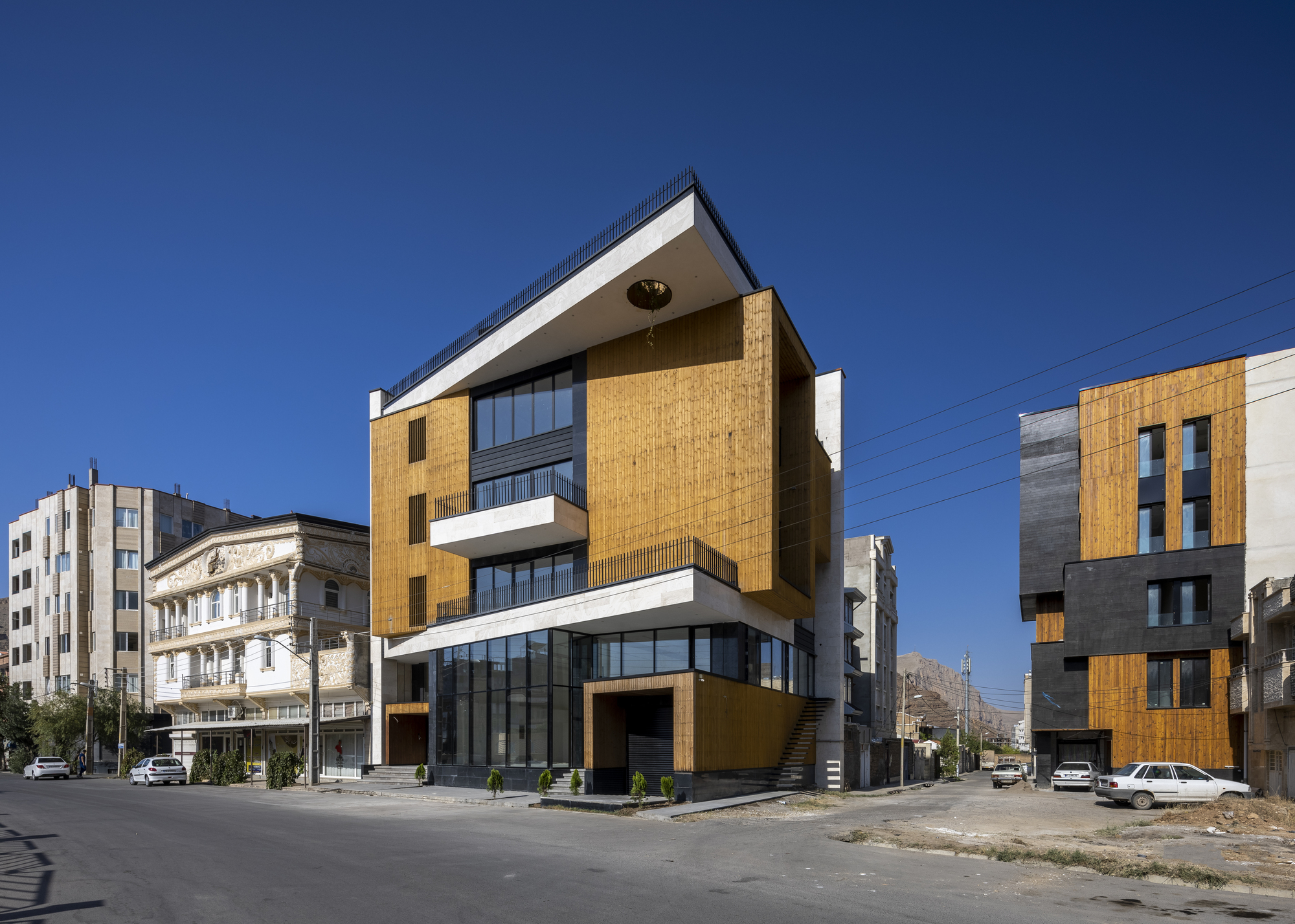 Corner facade showing alternating brick cladding and white horizontal bands with glazed ground floor
