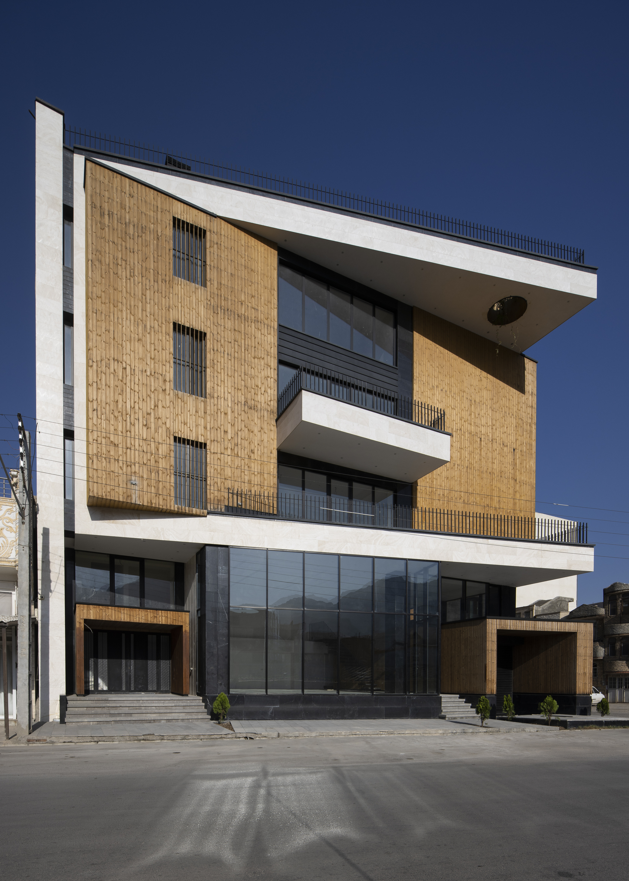 Front elevation featuring vertically layered timber panels and recessed balconies with metal railings
