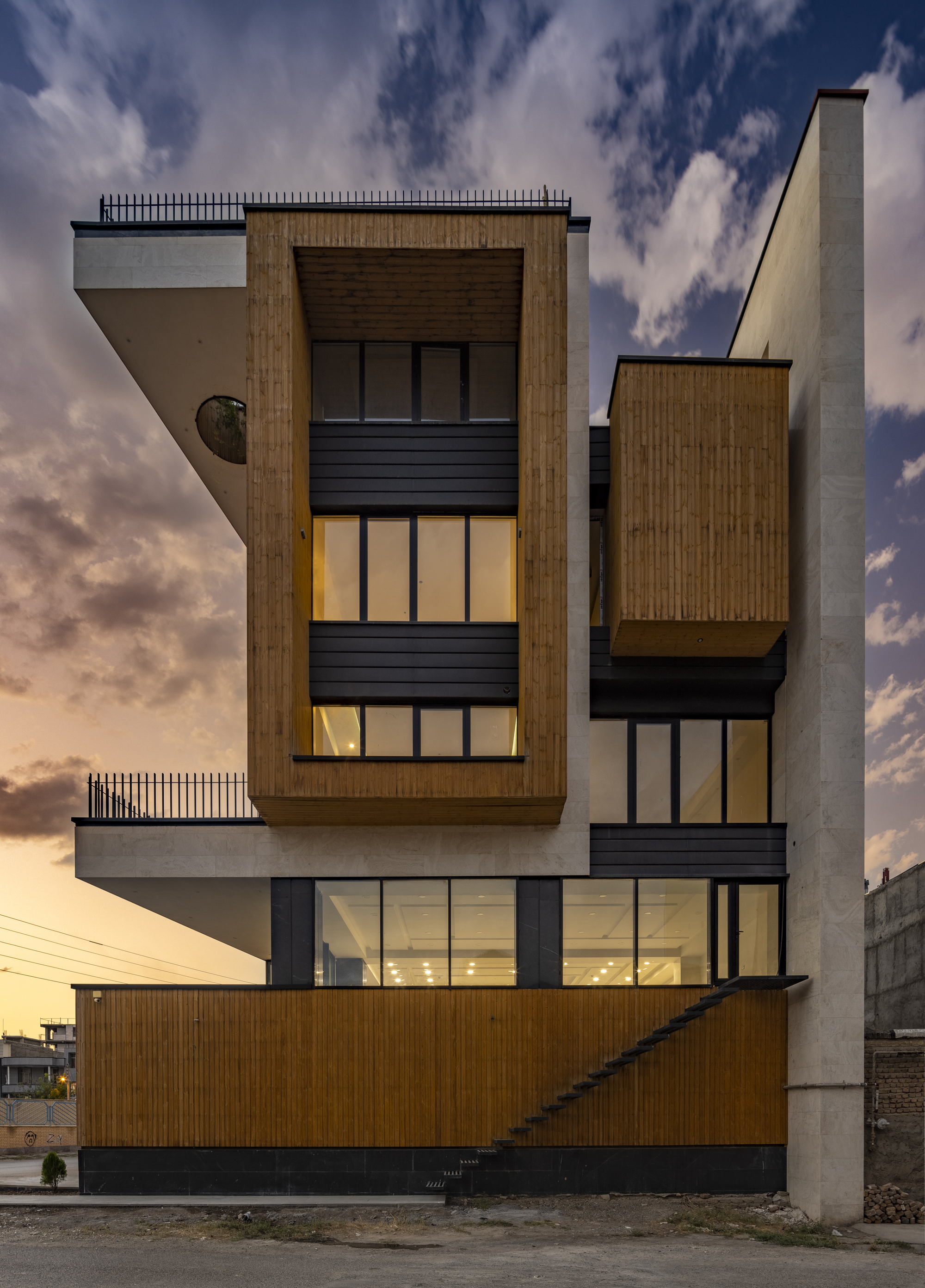 Rear facade with timber cladding and dark metal panels illuminated at dusk
