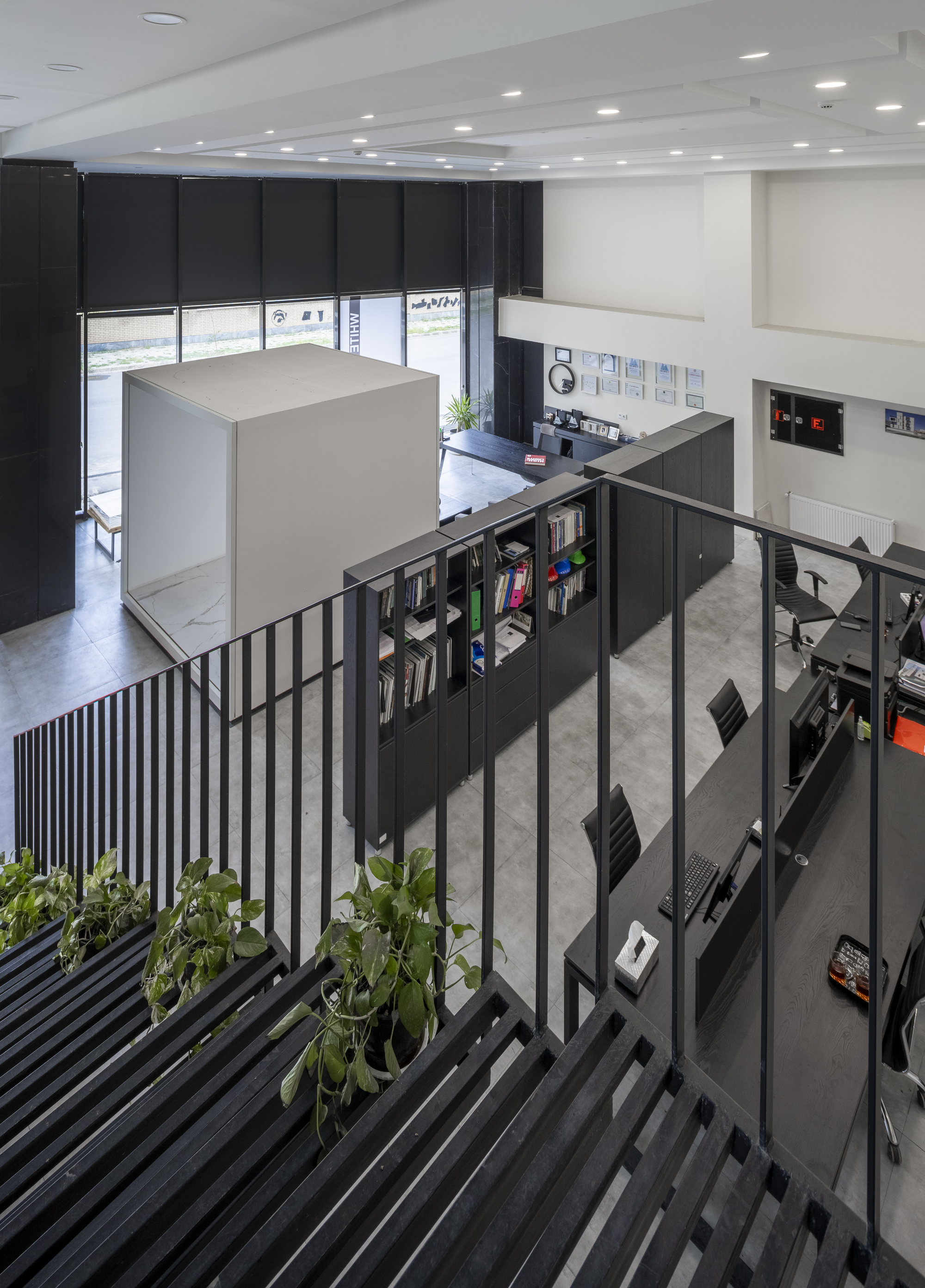 View down the steel staircase with planted treads overlooking the double-height library space with black shelving