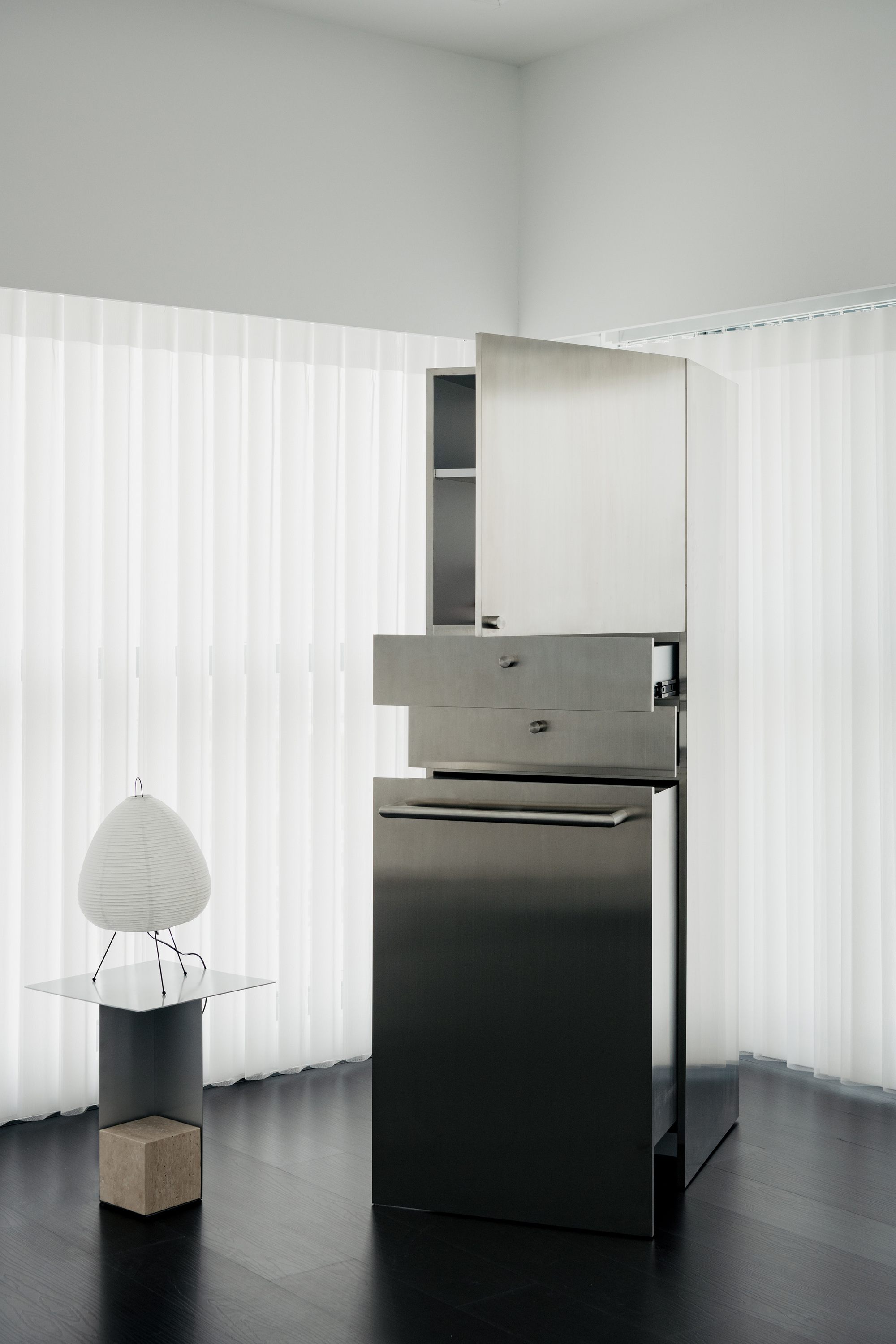Freestanding kitchen counter with grey drawers and black cabinetry against translucent corrugated wall panels