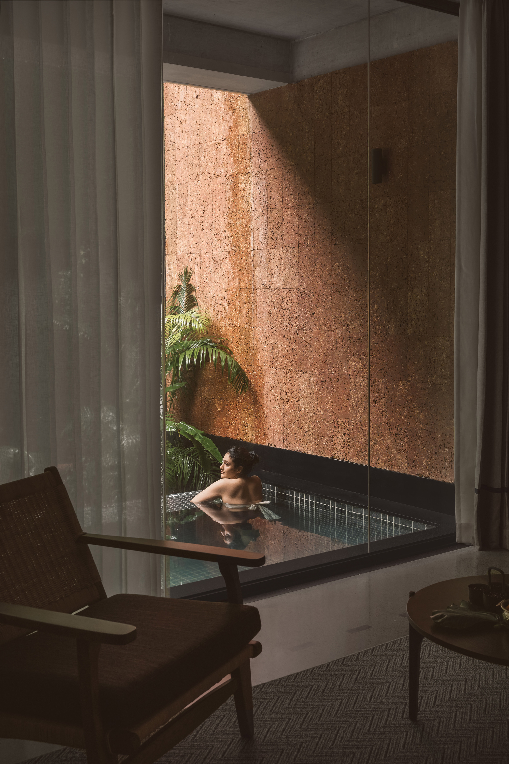 Interior view of a plunge pool with cork-clad walls and a palm tree reflected in still water
