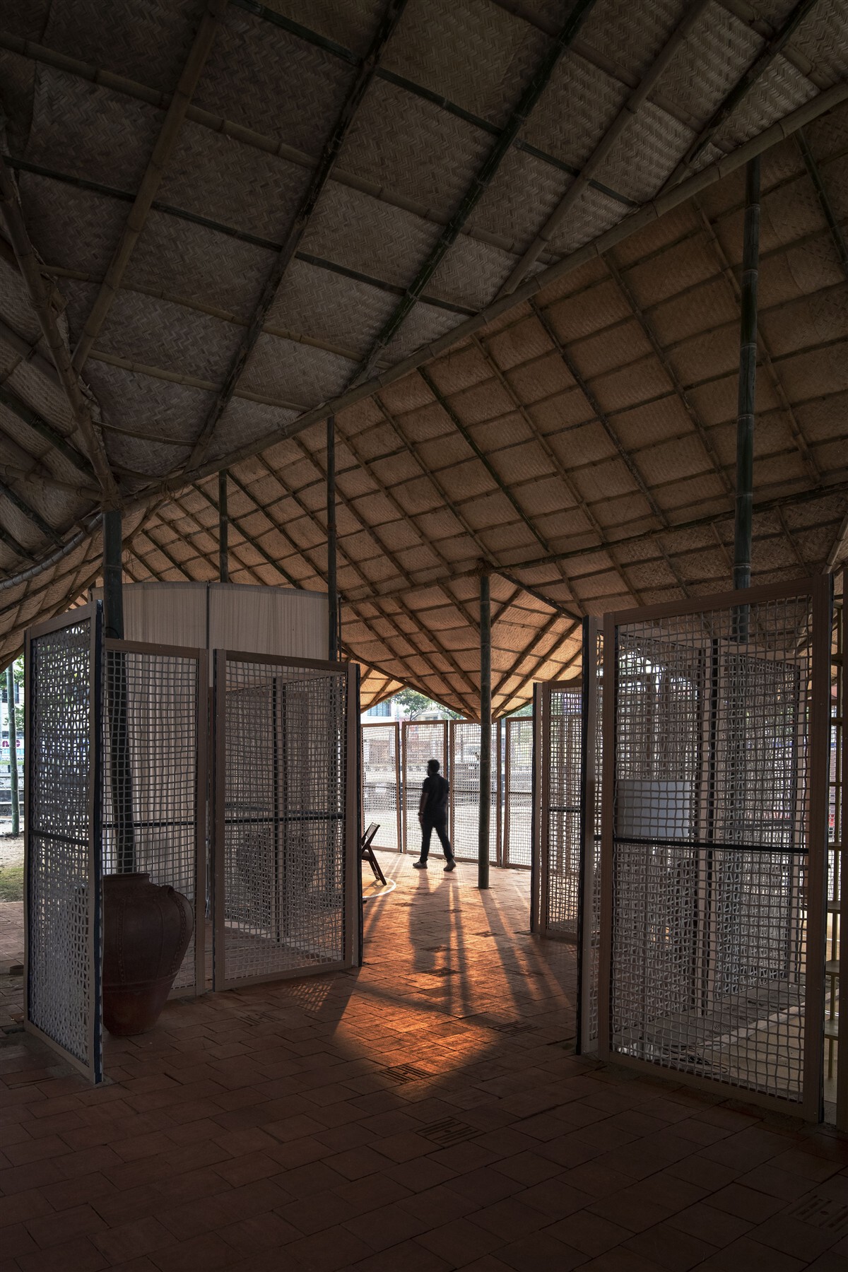 Interior corridor with perforated metal screens and exposed timber trusses filtering afternoon sunlight