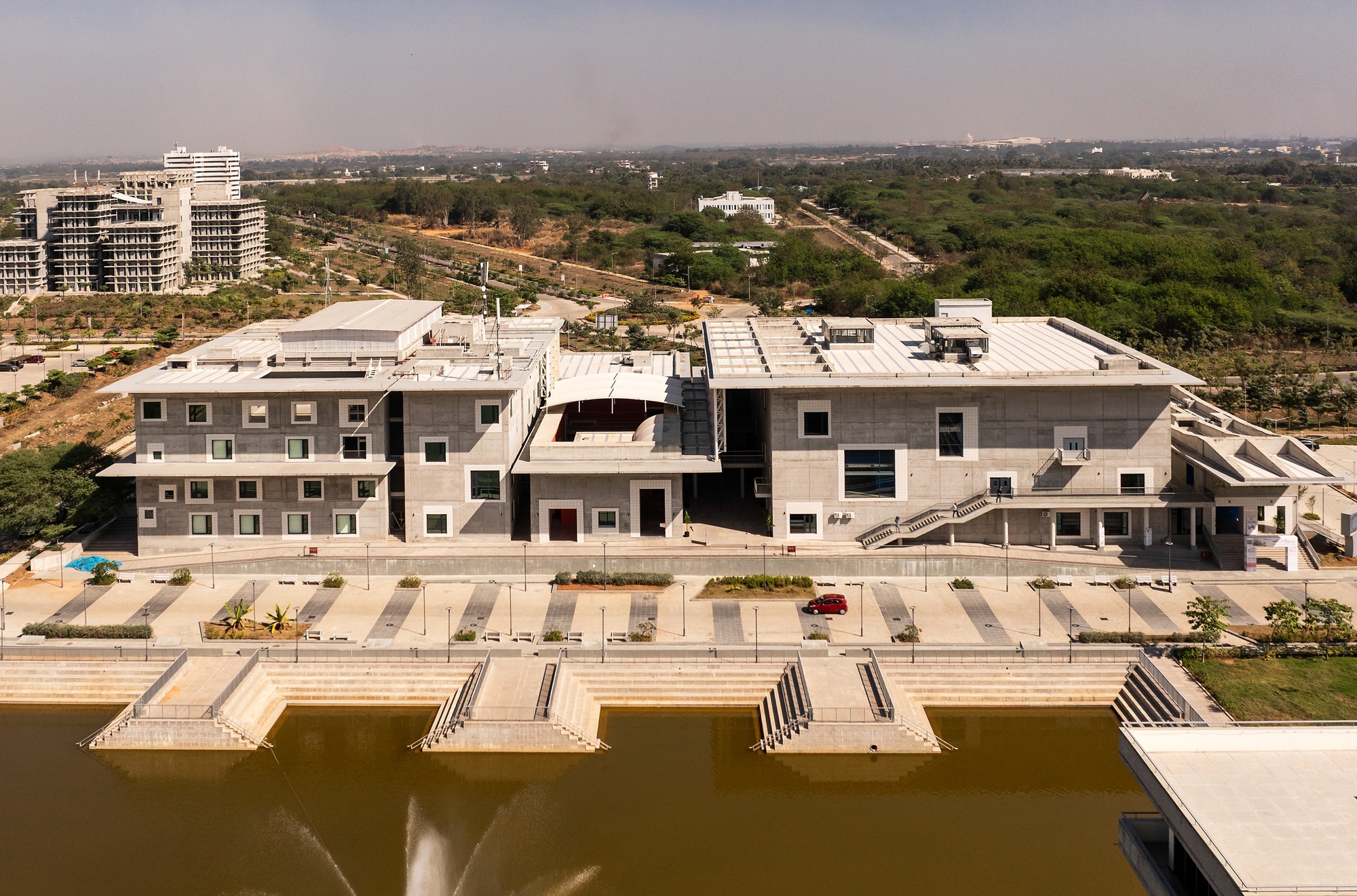 Aerial view of the concrete complex with flat roofs and stepped terraces along a waterfront plaza