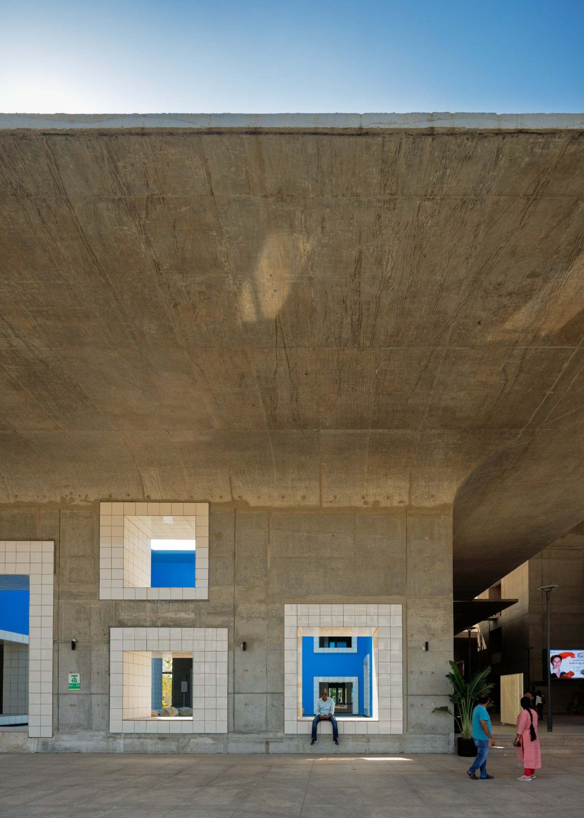 Vaulted concrete ceiling above tile-framed apertures looking out to visitors under afternoon sunlight