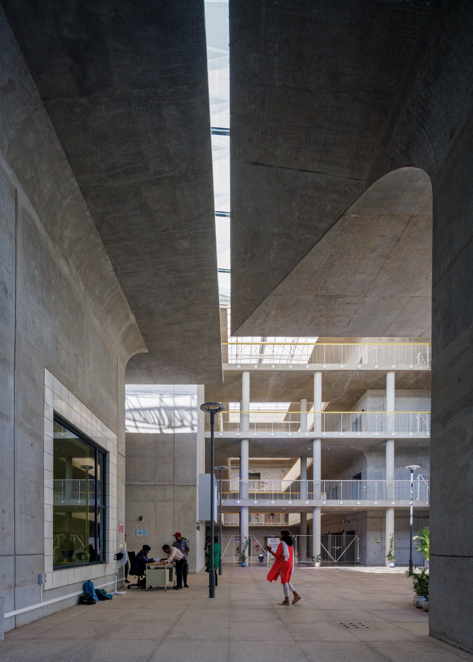 Multi-story atrium with exposed concrete ceilings and curved vaults illuminated by a central skylight slot