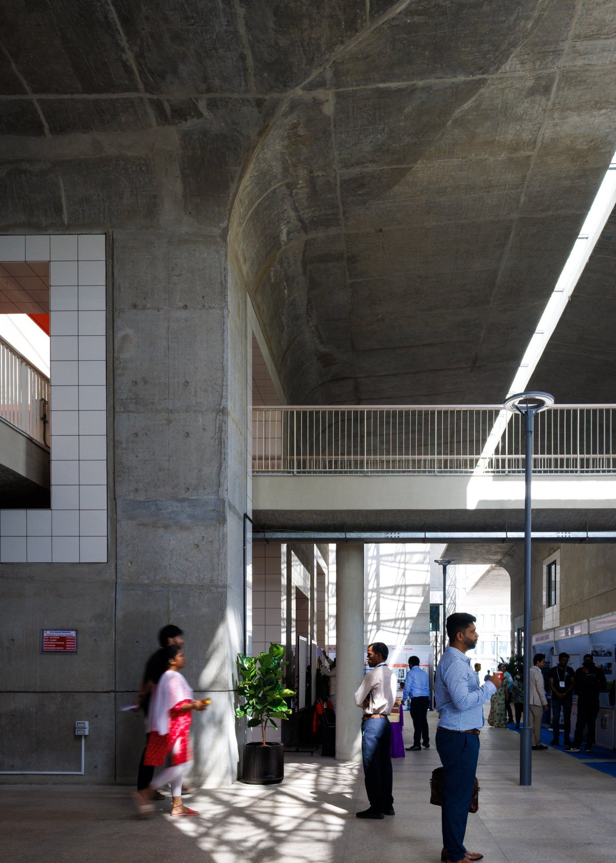 Ground floor circulation space with concrete columns and metal railings beneath an arched vault