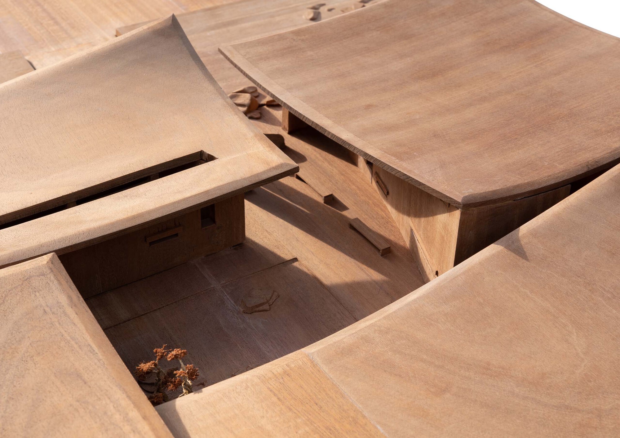Physical model showing intersecting roof planes and a sunken courtyard with a small tree