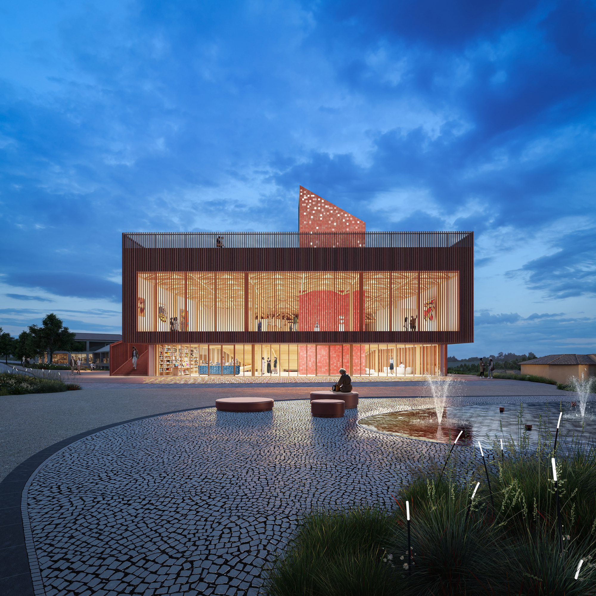 Illuminated glass facade with perforated red metal screen and triangular rooftop element at dusk