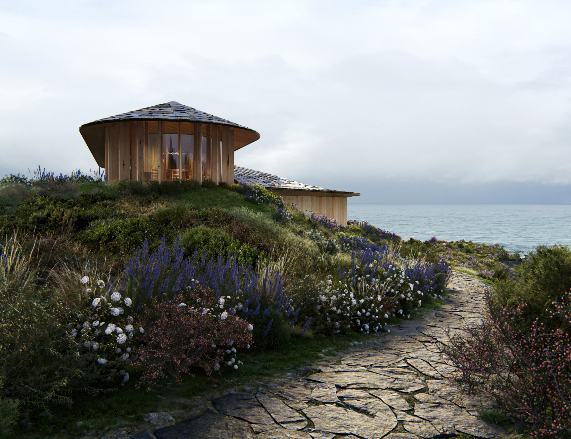 Cylindrical timber pavilion with glazed walls on a coastal hillside planted with lavender and roses