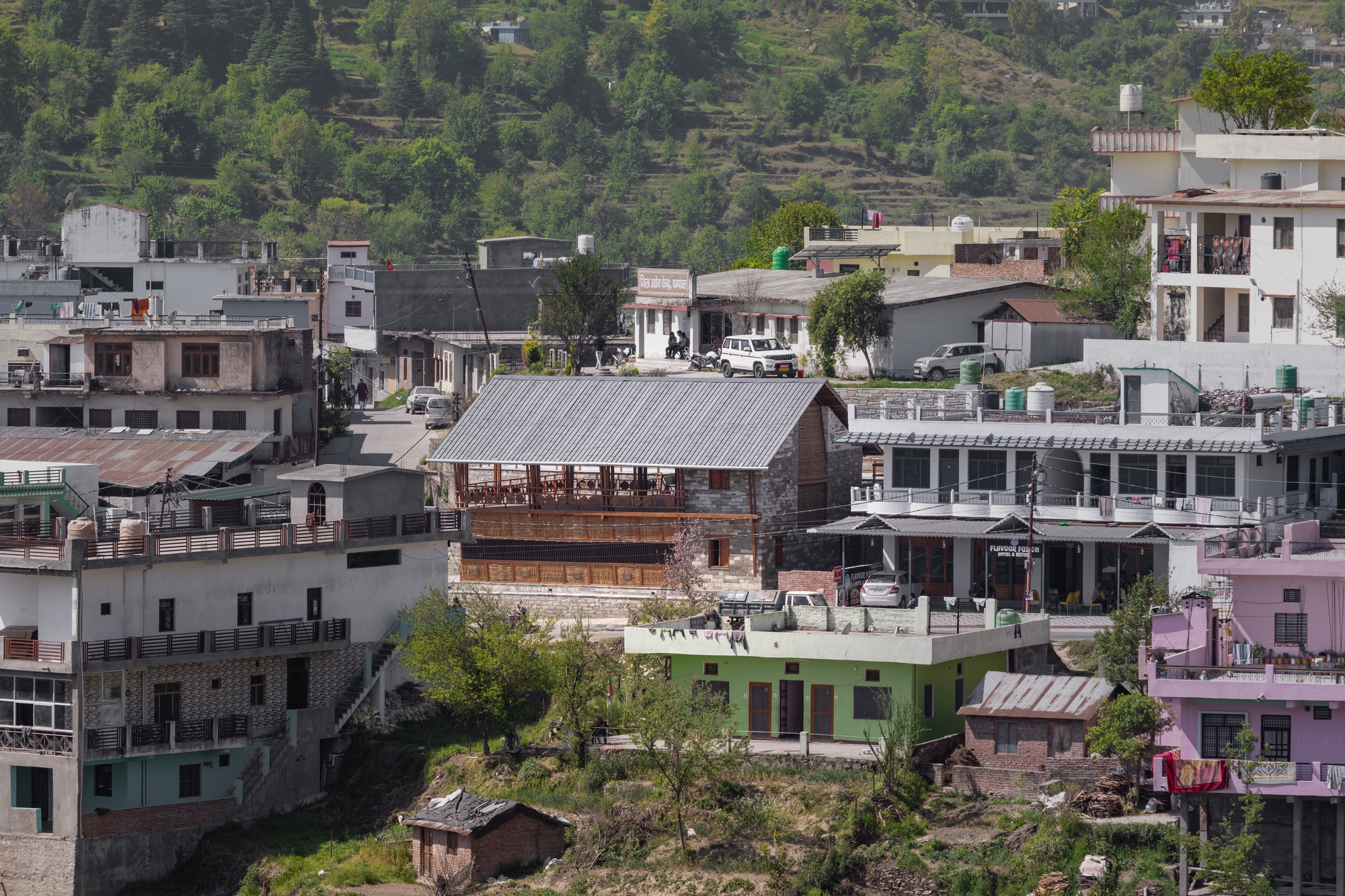 Mid-distance view of a timber and stone two-story house among surrounding concrete residential buildings