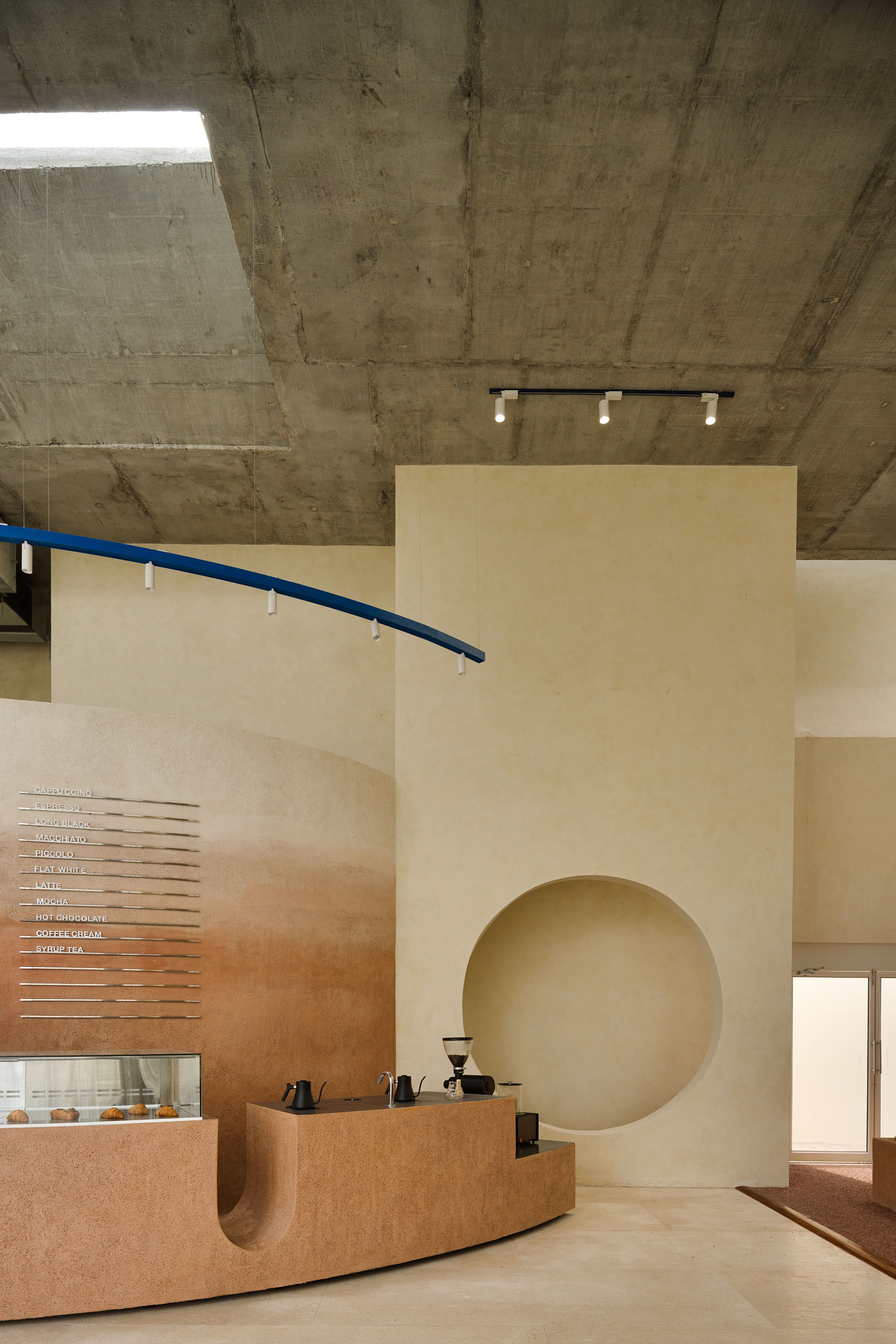 Interior view showing curved blue handrail and freestanding wall with circular opening