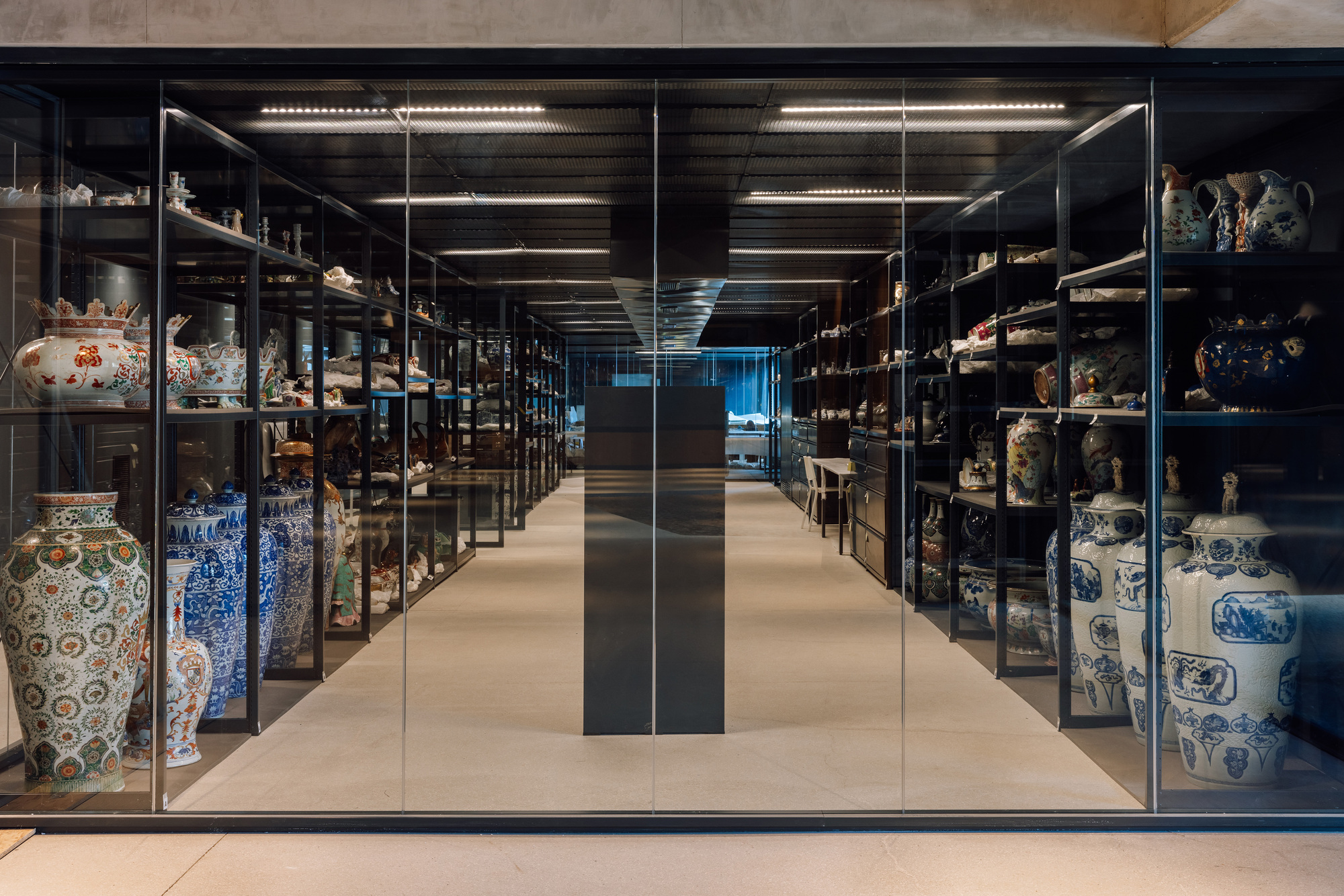 Black framed glass cabinets displaying porcelain vessels in a climate-controlled storage gallery with linear lighting