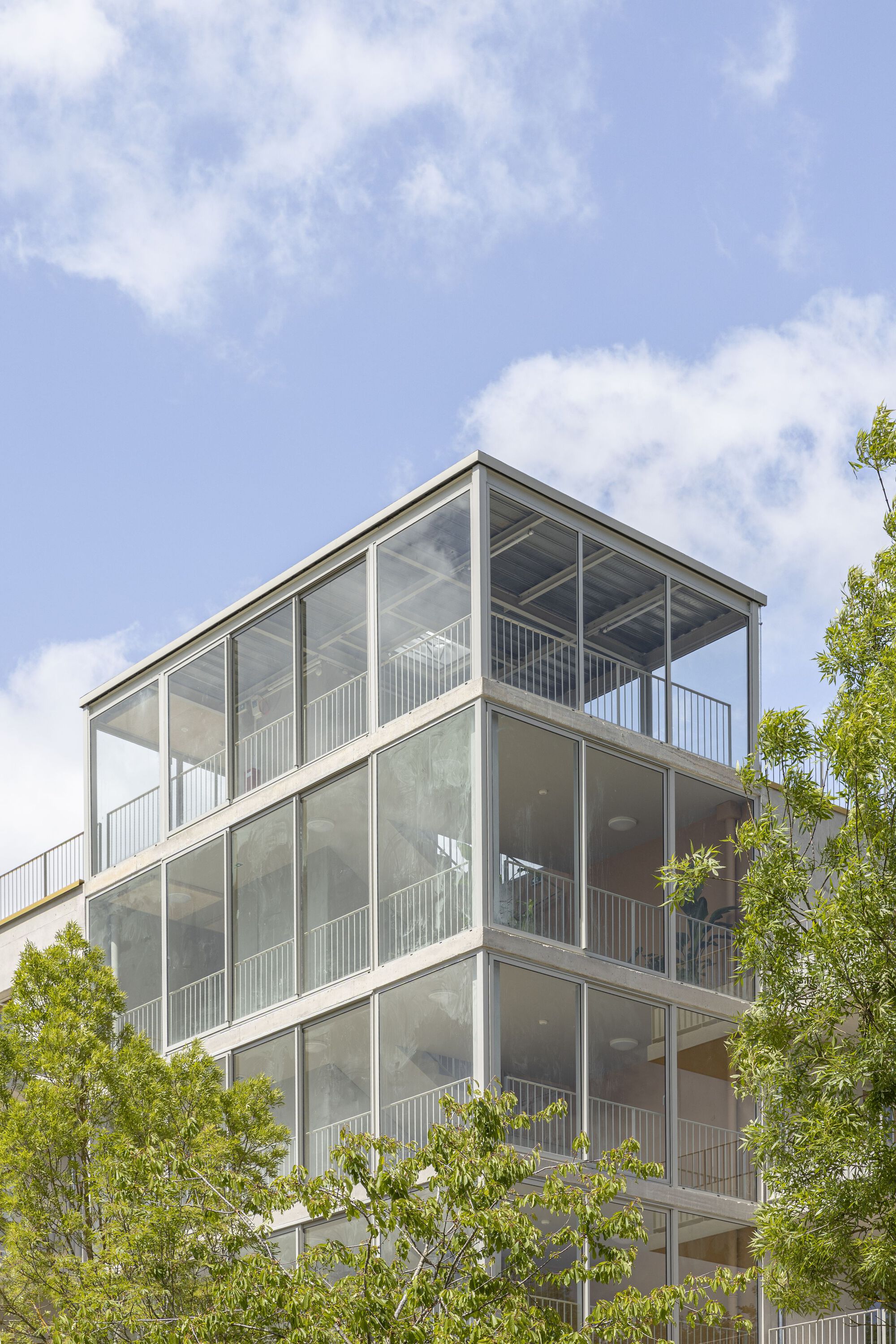 Upper floors of the glazed balcony stack with exposed ceiling slabs visible through transparent panels