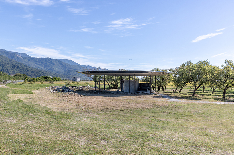 Long view of the pavilion roof in open grassland with mountain range beyond