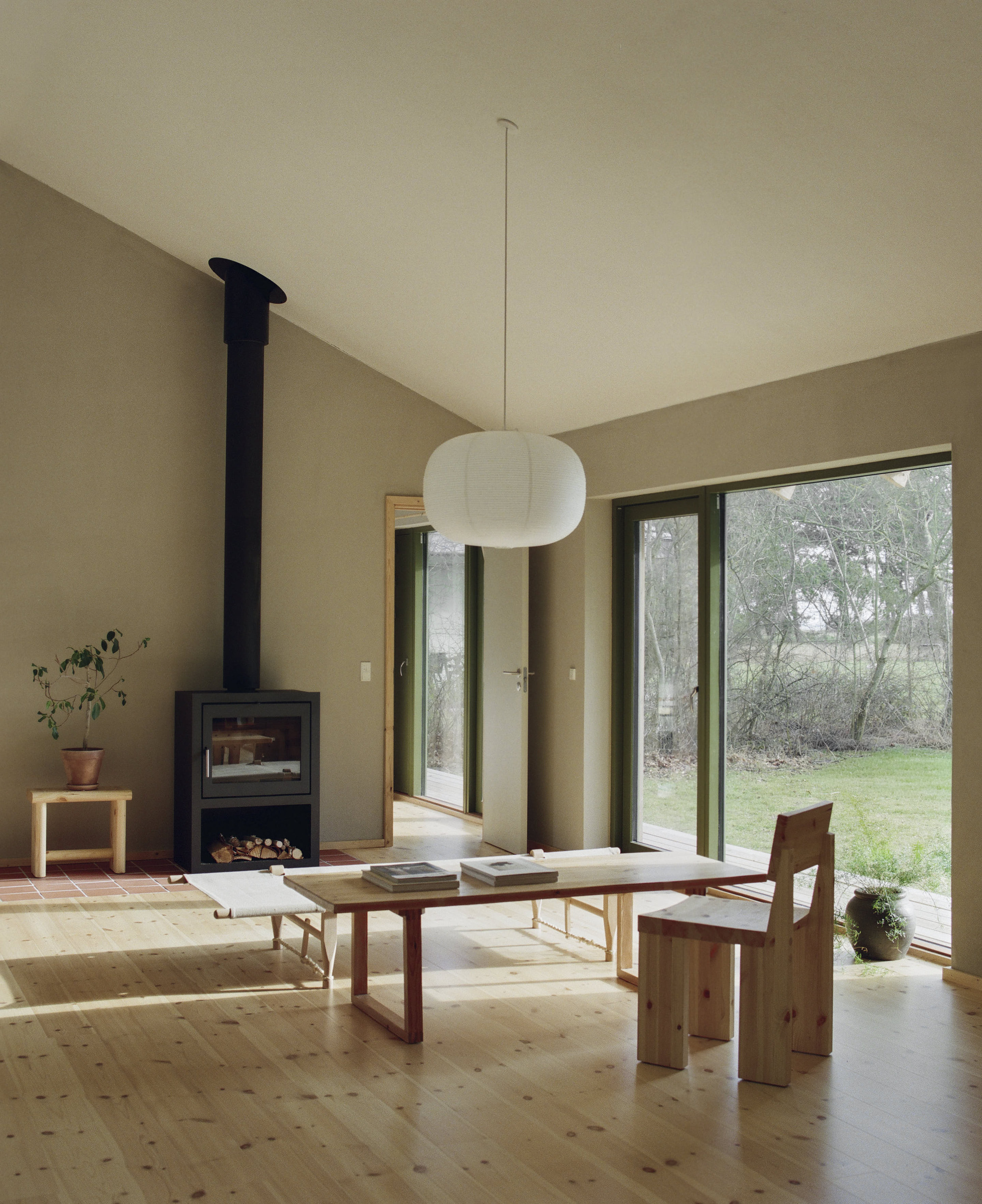 Living space with black wood stove, low table, and glass doors opening to garden