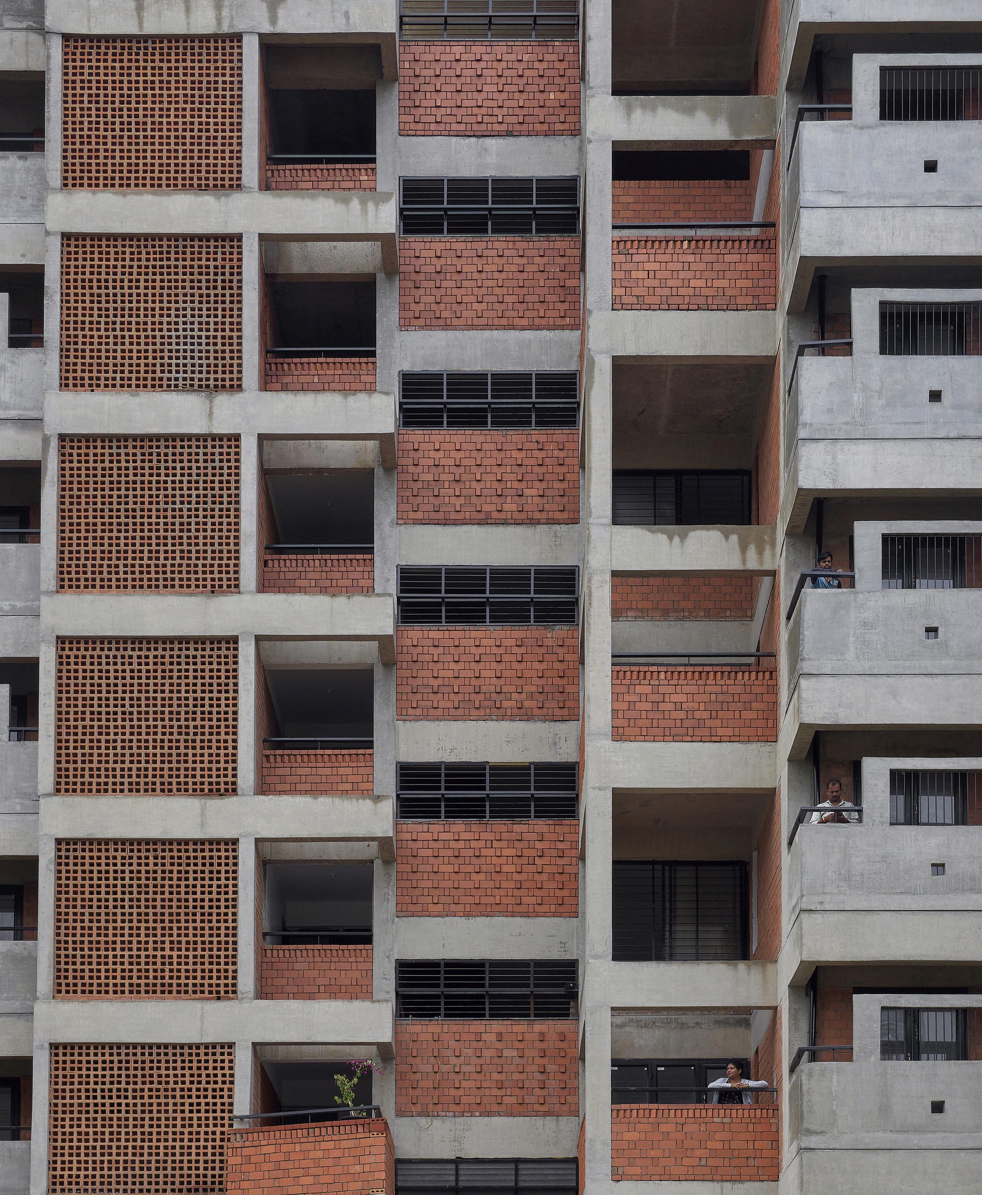 Facade elevation showing alternating concrete frames with perforated brick screens and recessed balconies