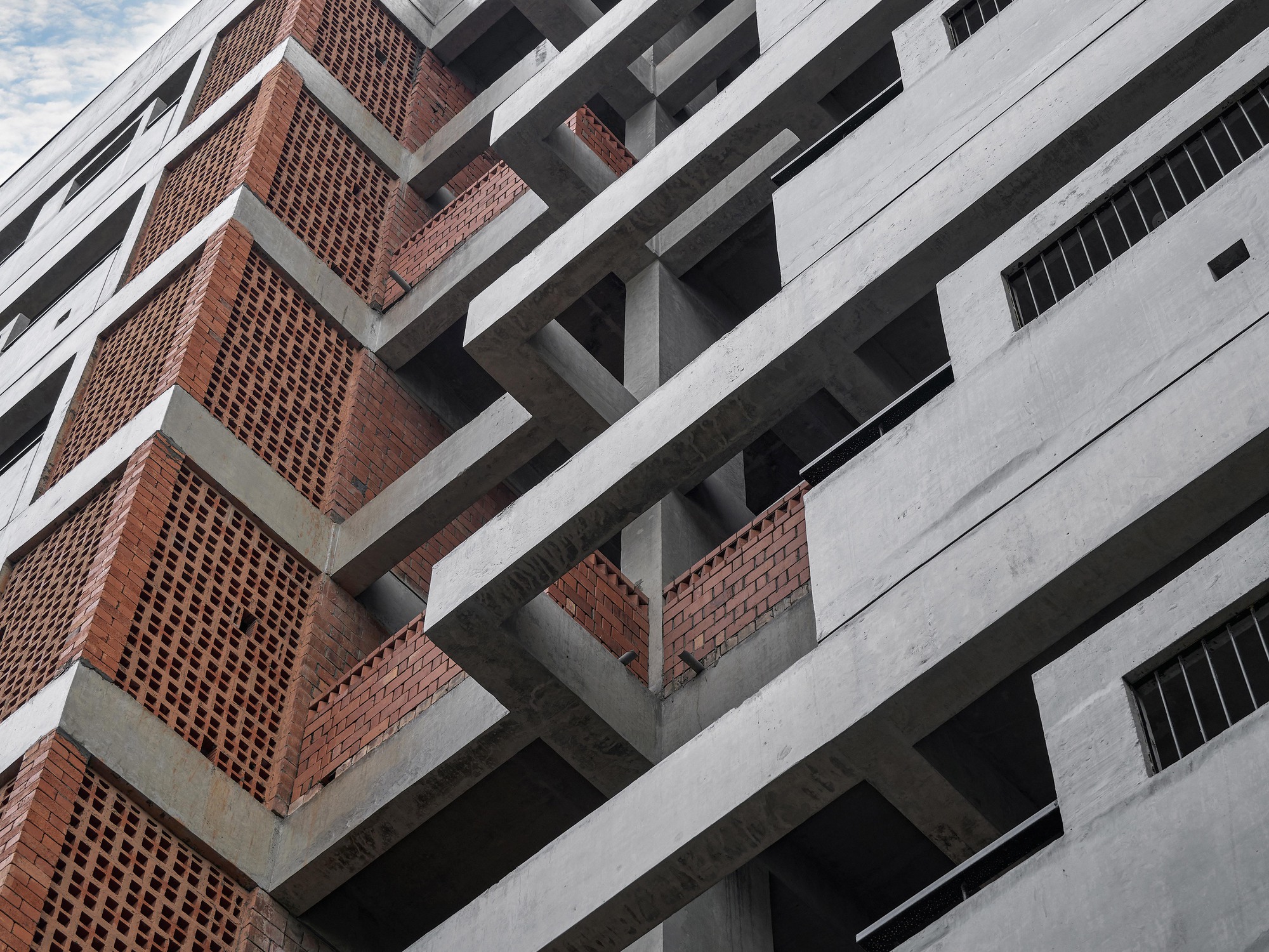Angled view of the intersecting concrete slab edges and perforated brick screen panels