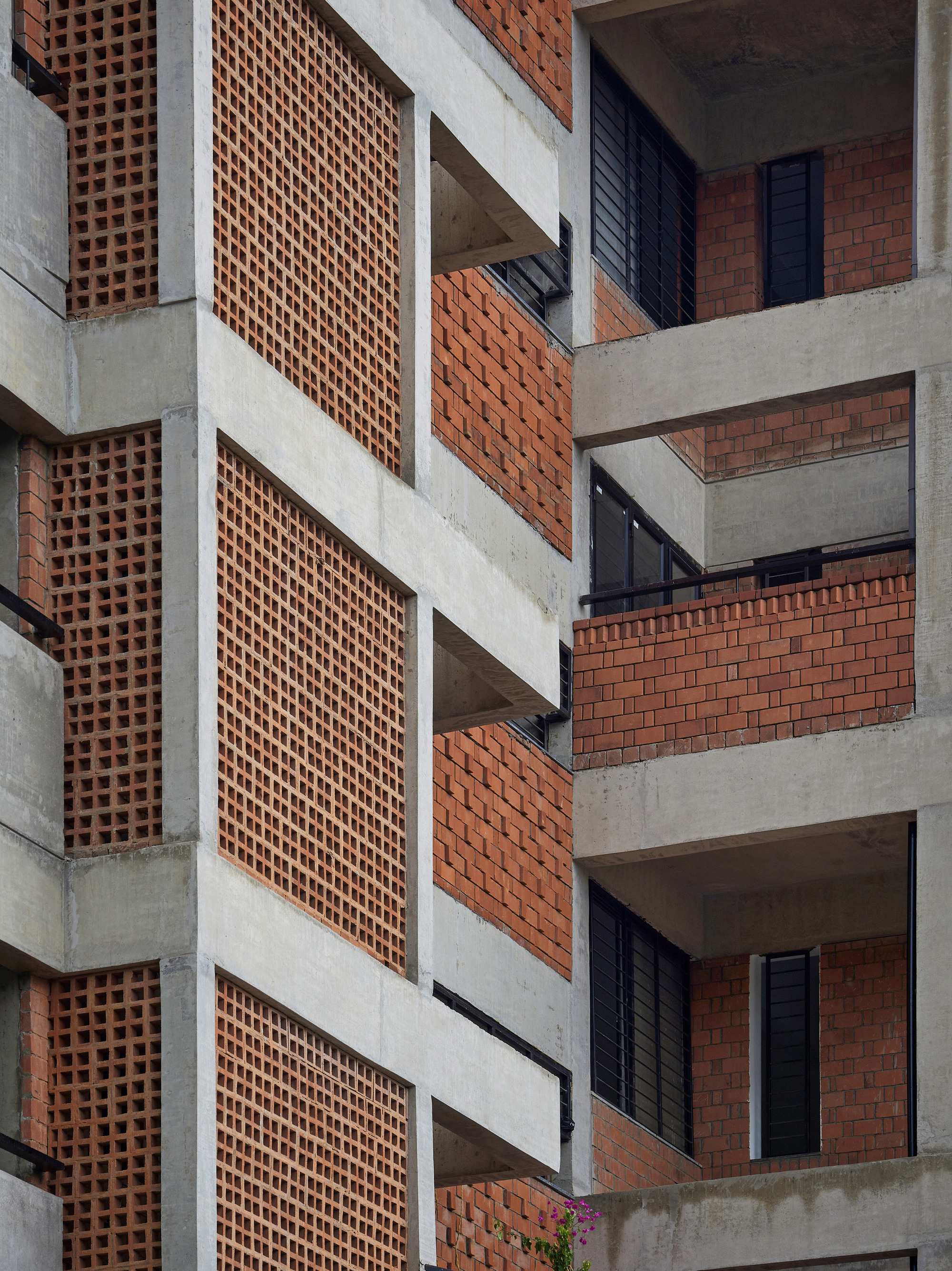 Facade detail of concrete frame with perforated terracotta brick screens and recessed balconies