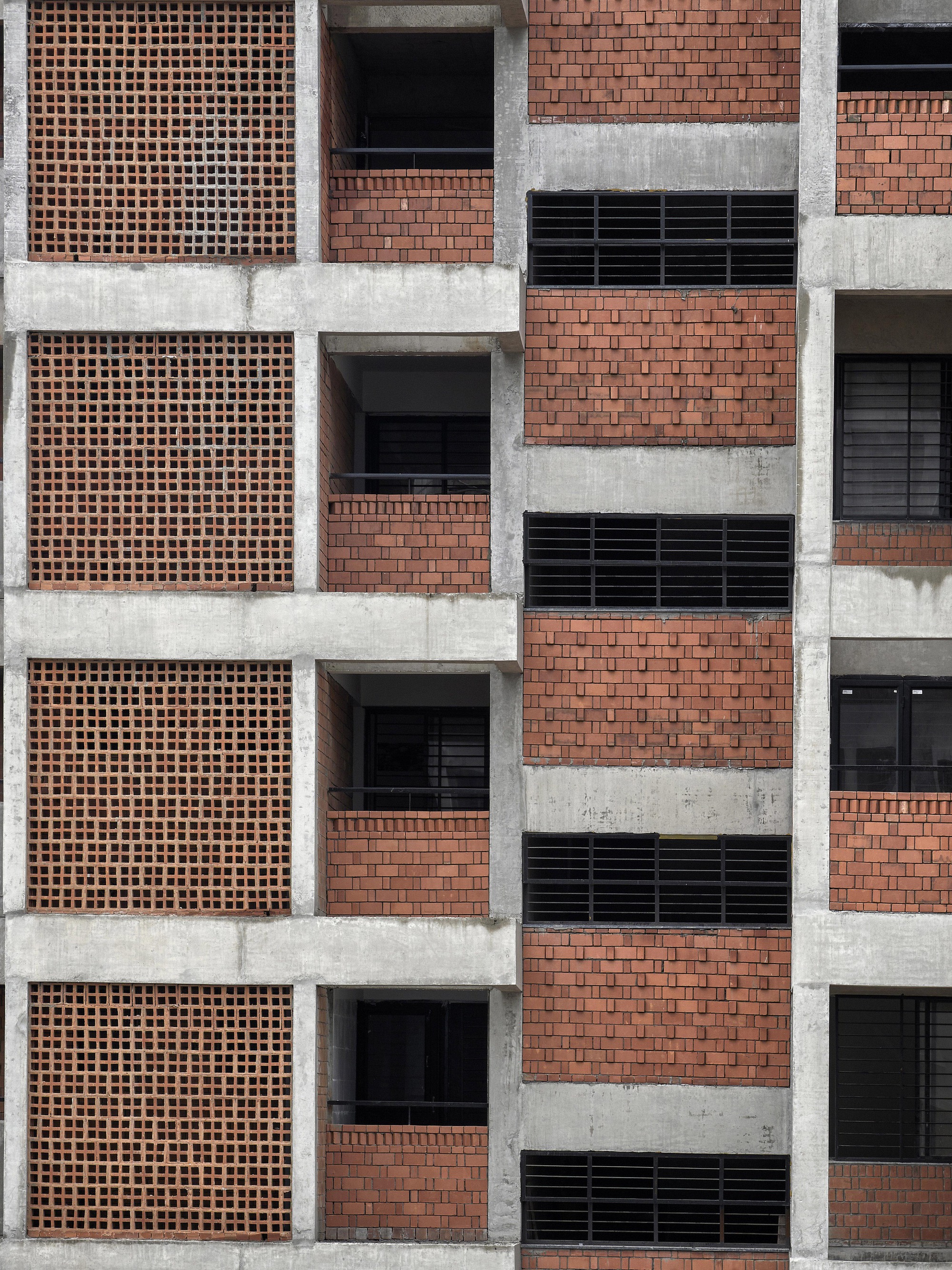 Flat frontal view of the gridded facade with terracotta brick screens and horizontal concrete bands